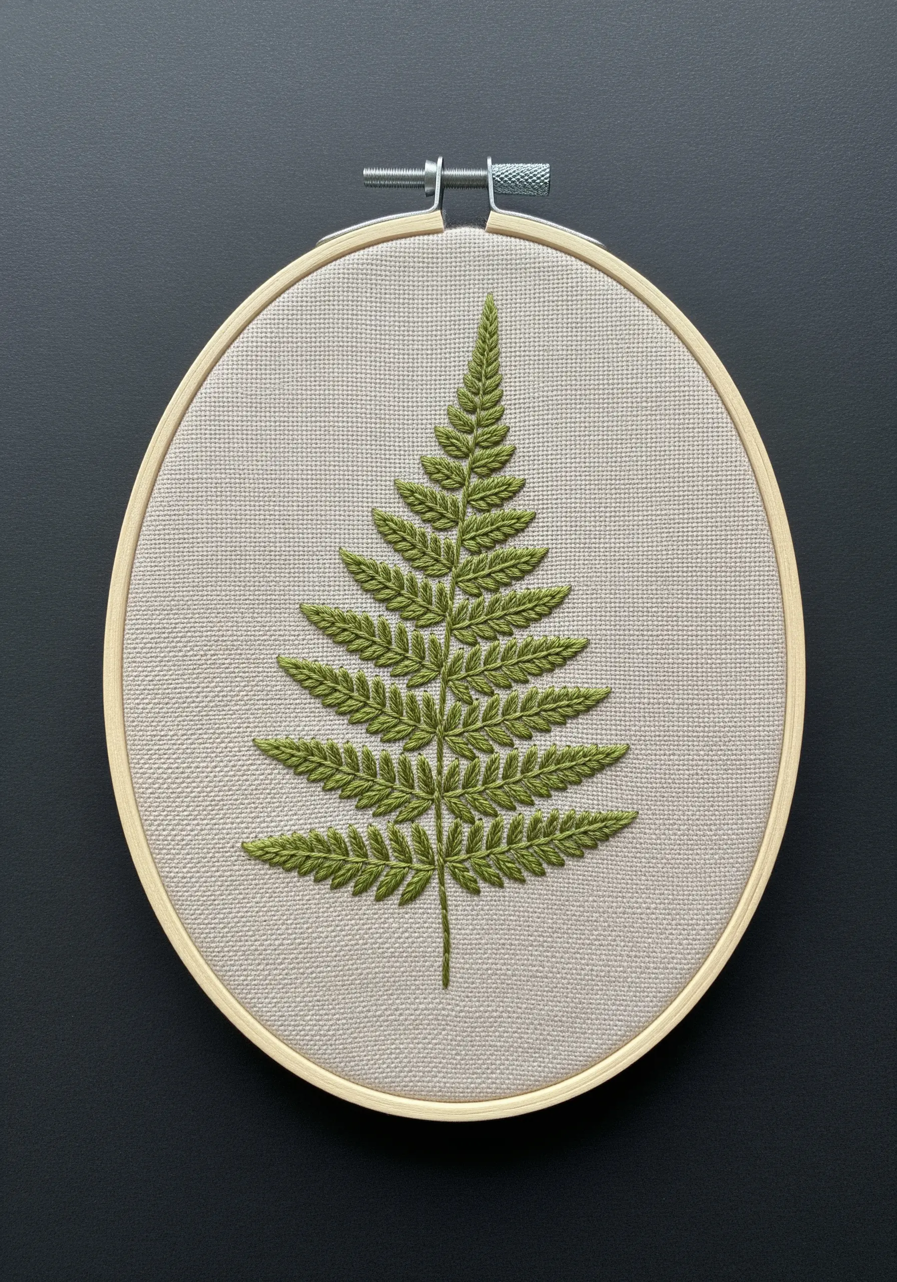 A detailed green fern leaf embroidered on light beige fabric.