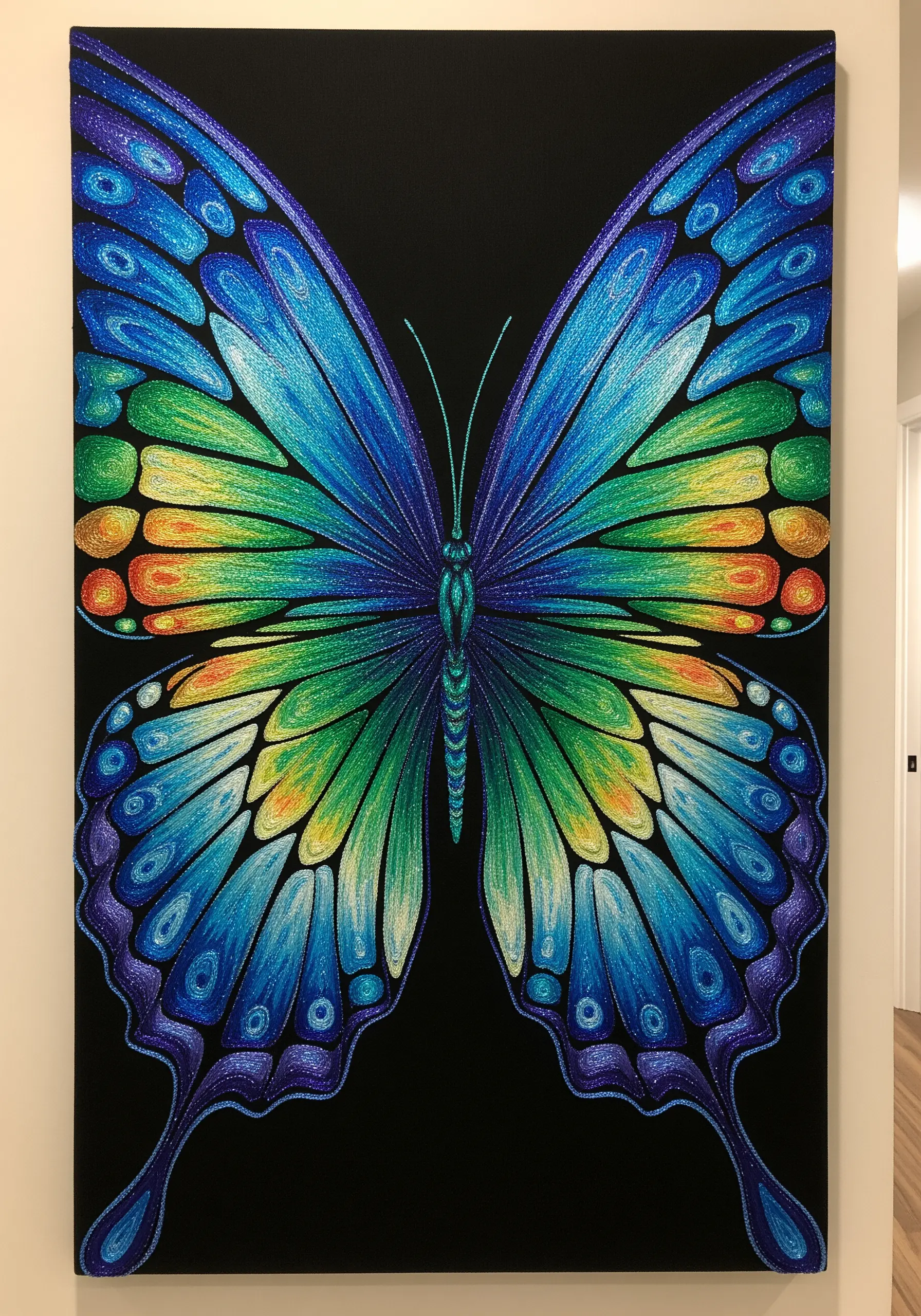 A large, vibrant thread-painted butterfly with iridescent blue, green, and yellow wings on black canvas.