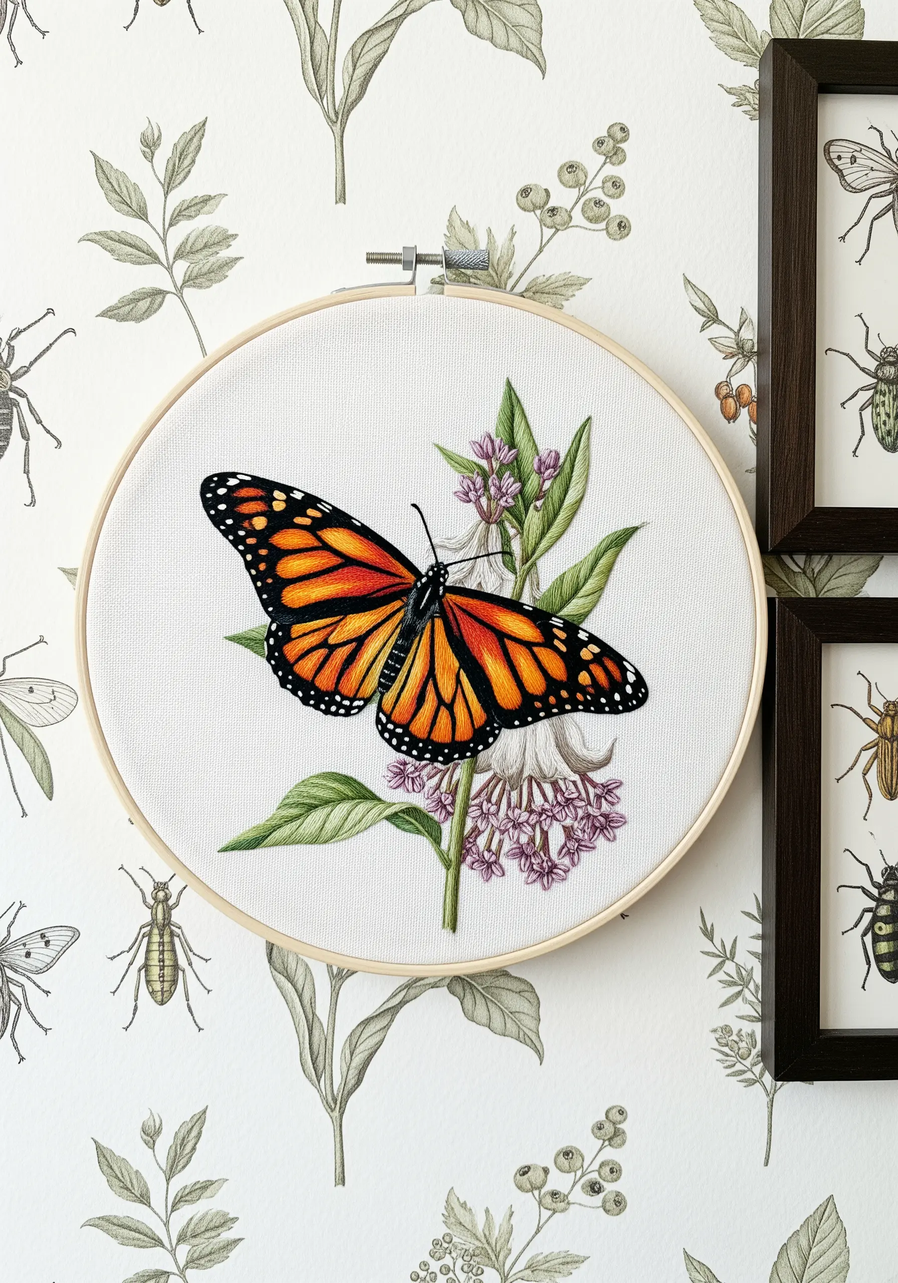 A realistic thread-painted monarch butterfly on milkweed, hung on a botanical wallpaper