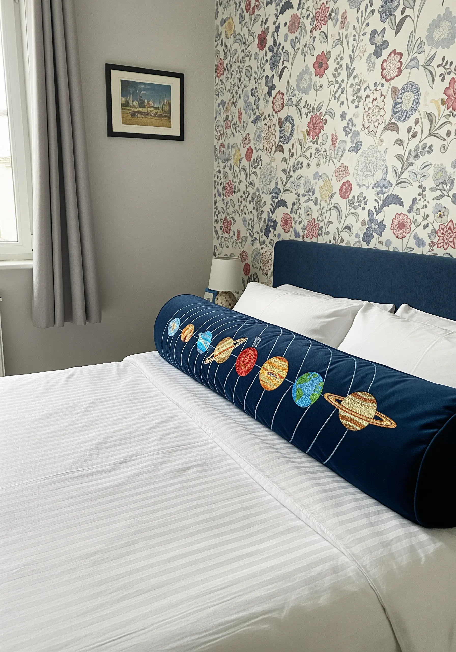 A row of colorful, satin-stitched planets on a long, navy blue bolster pillow.