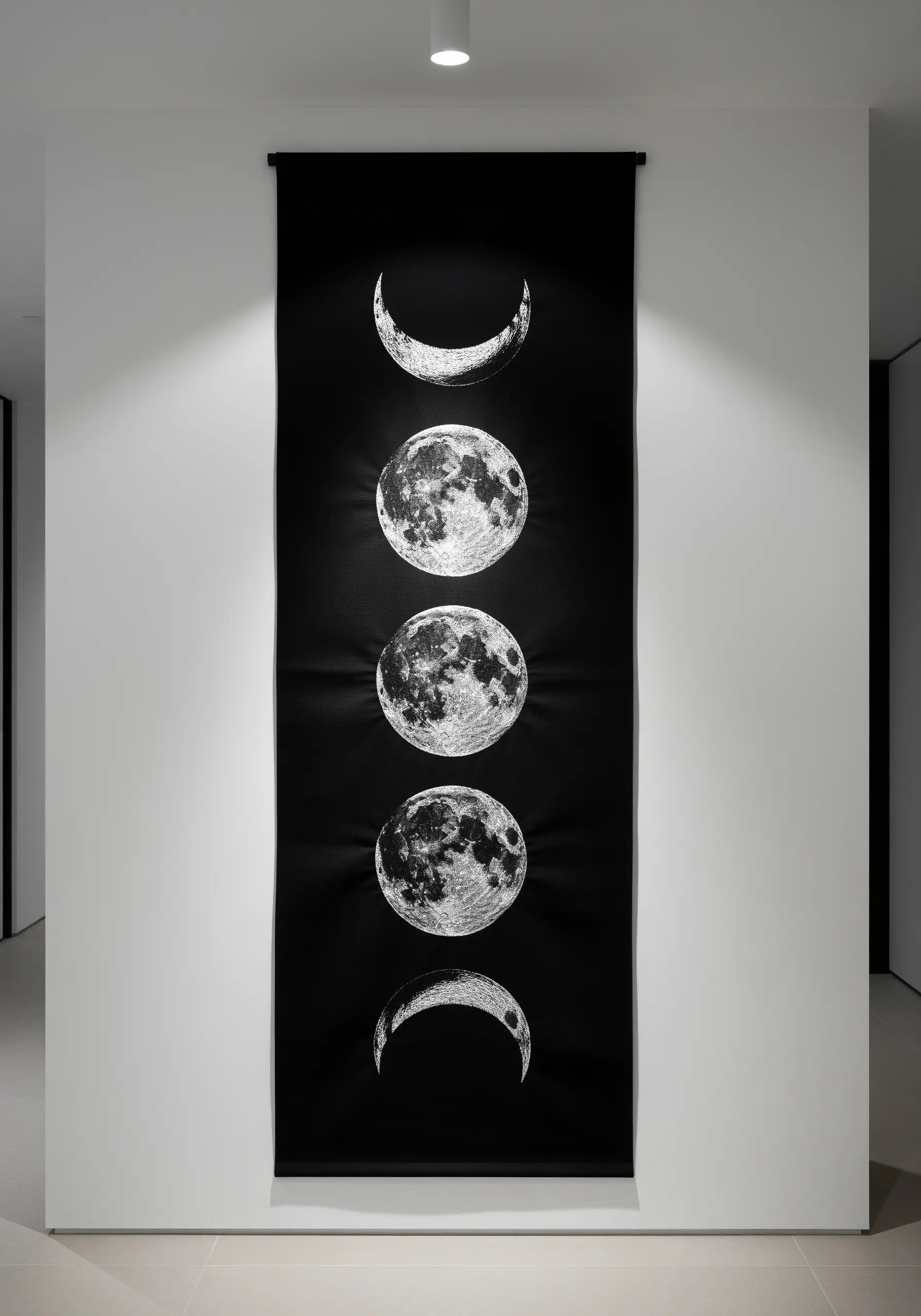 A long black wall hanging featuring five phases of the moon embroidered in silver metallic thread.