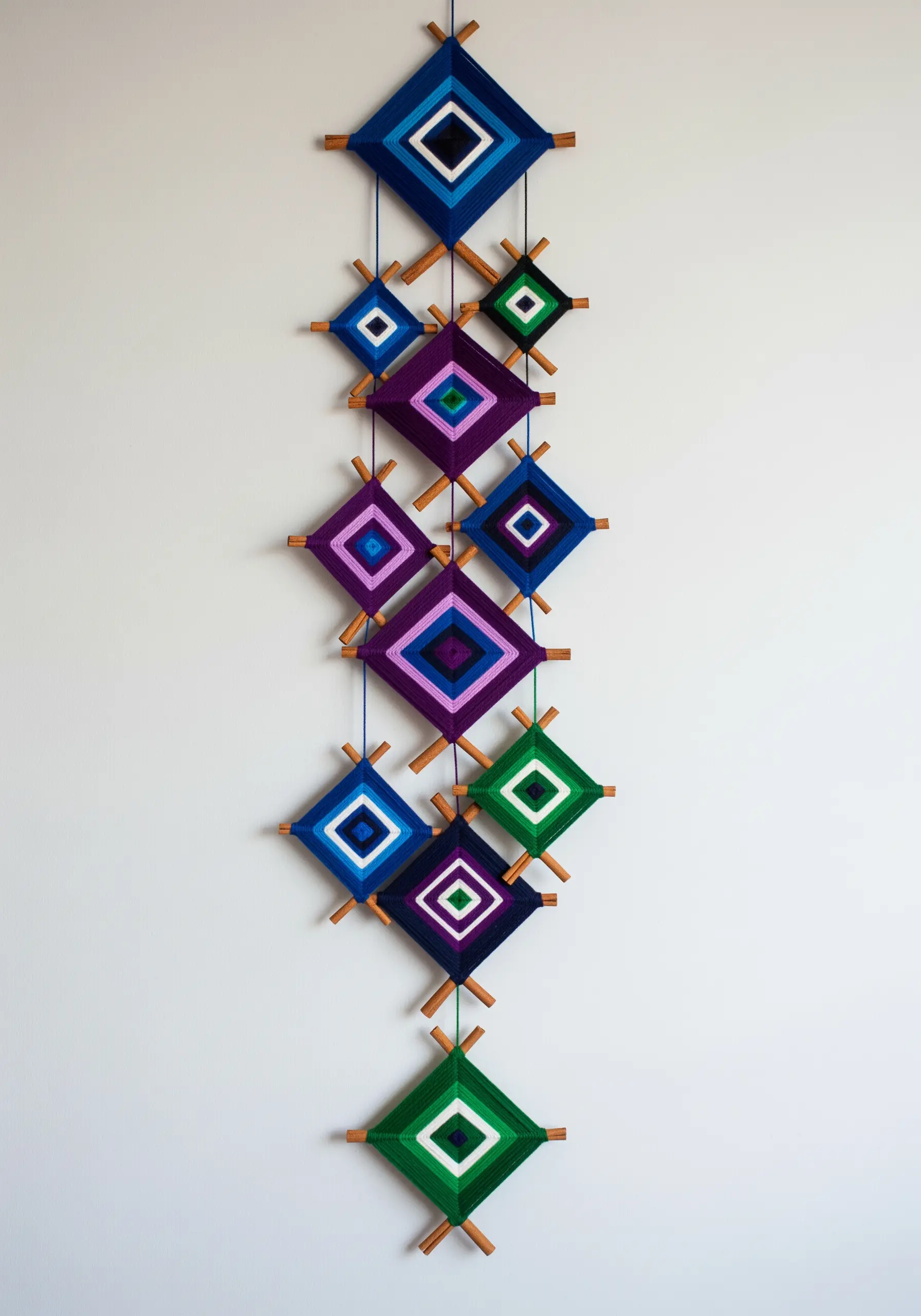 A hanging wall decoration made of multiple geometric Ojo de Dios yarn weavings.
