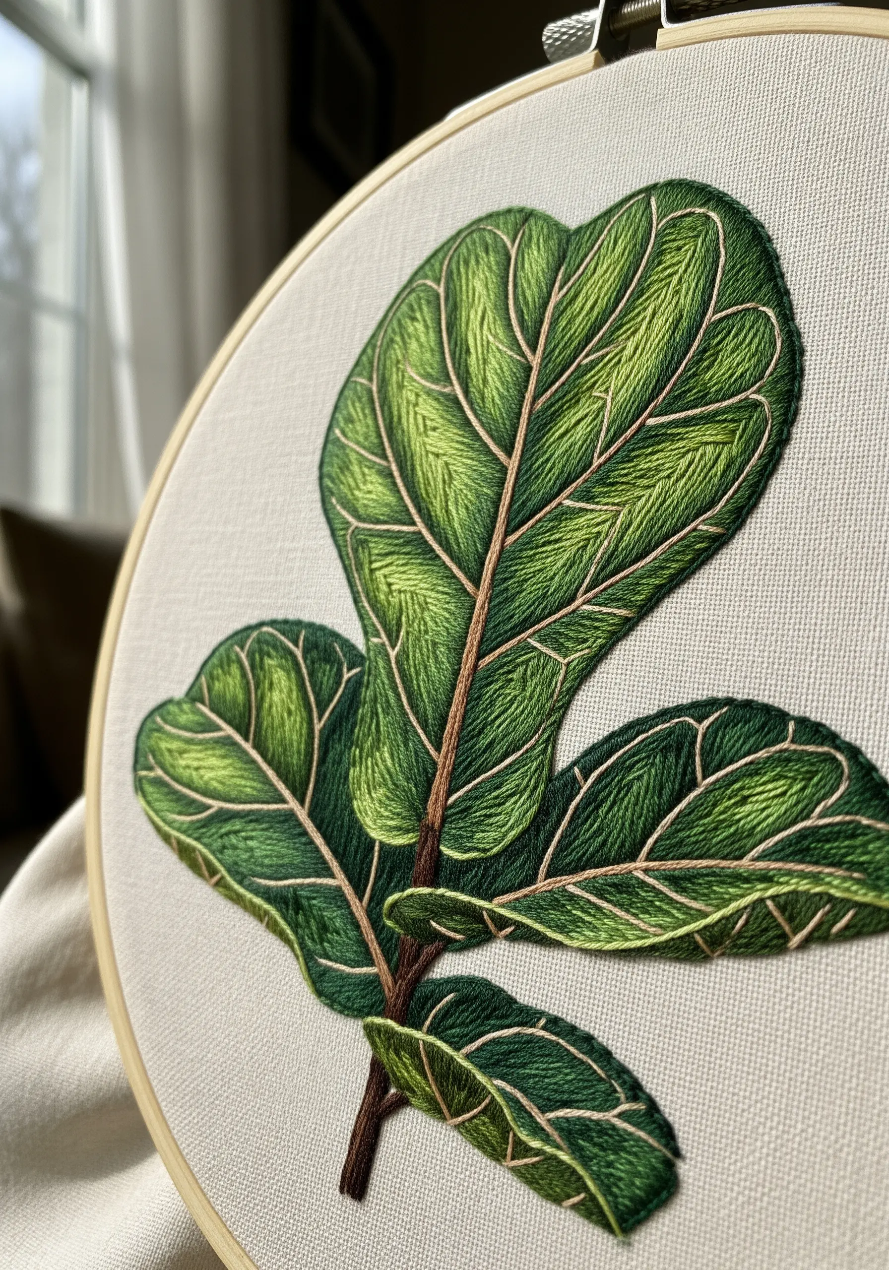 Close-up of a fiddle leaf fig embroidery showing blended green thread painting.
