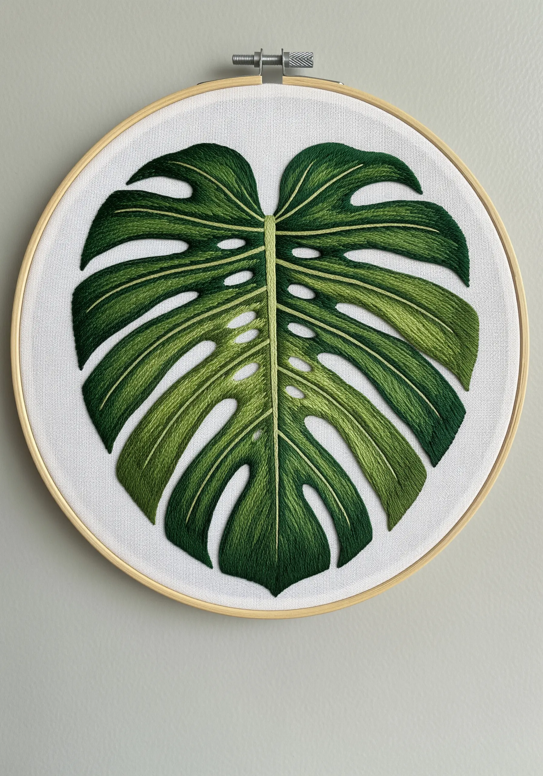 A highly detailed, thread-painted Monstera deliciosa leaf in an embroidery hoop.