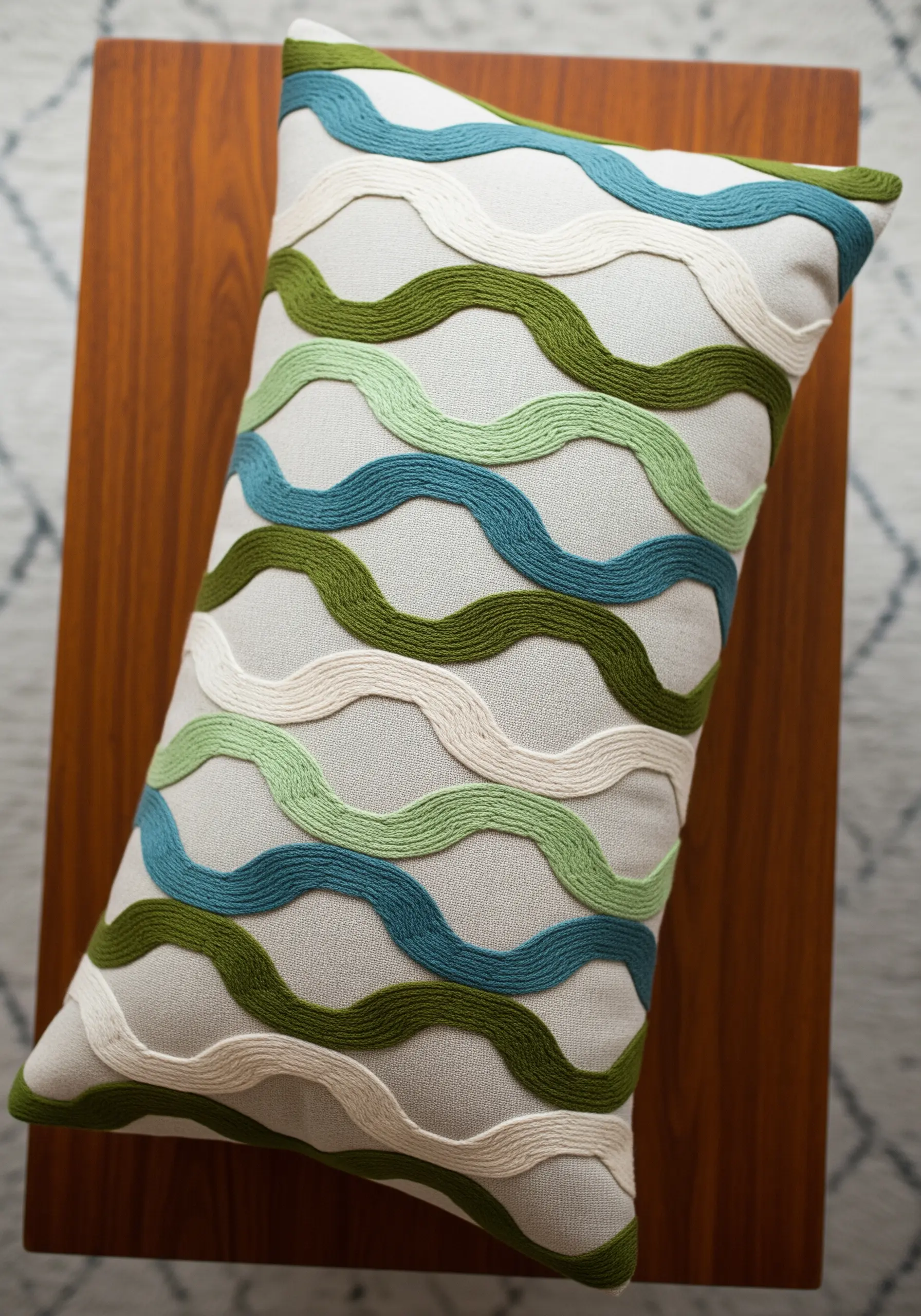 Wavy lines in green and blue hues embroidered with a raised, rope-like stitch technique.