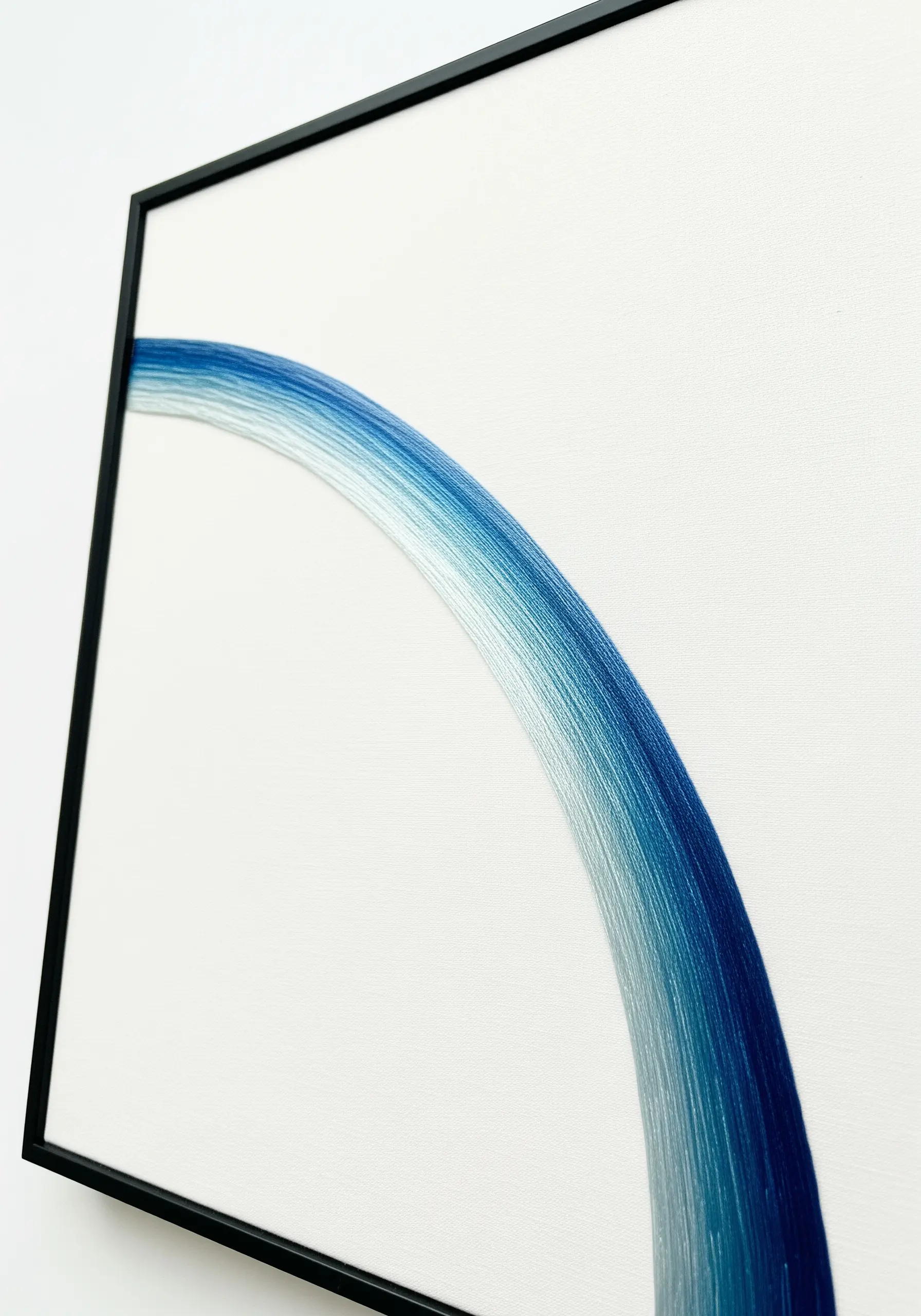 A minimalist, perfectly smooth gradient of blue thread forming an arch on white canvas.