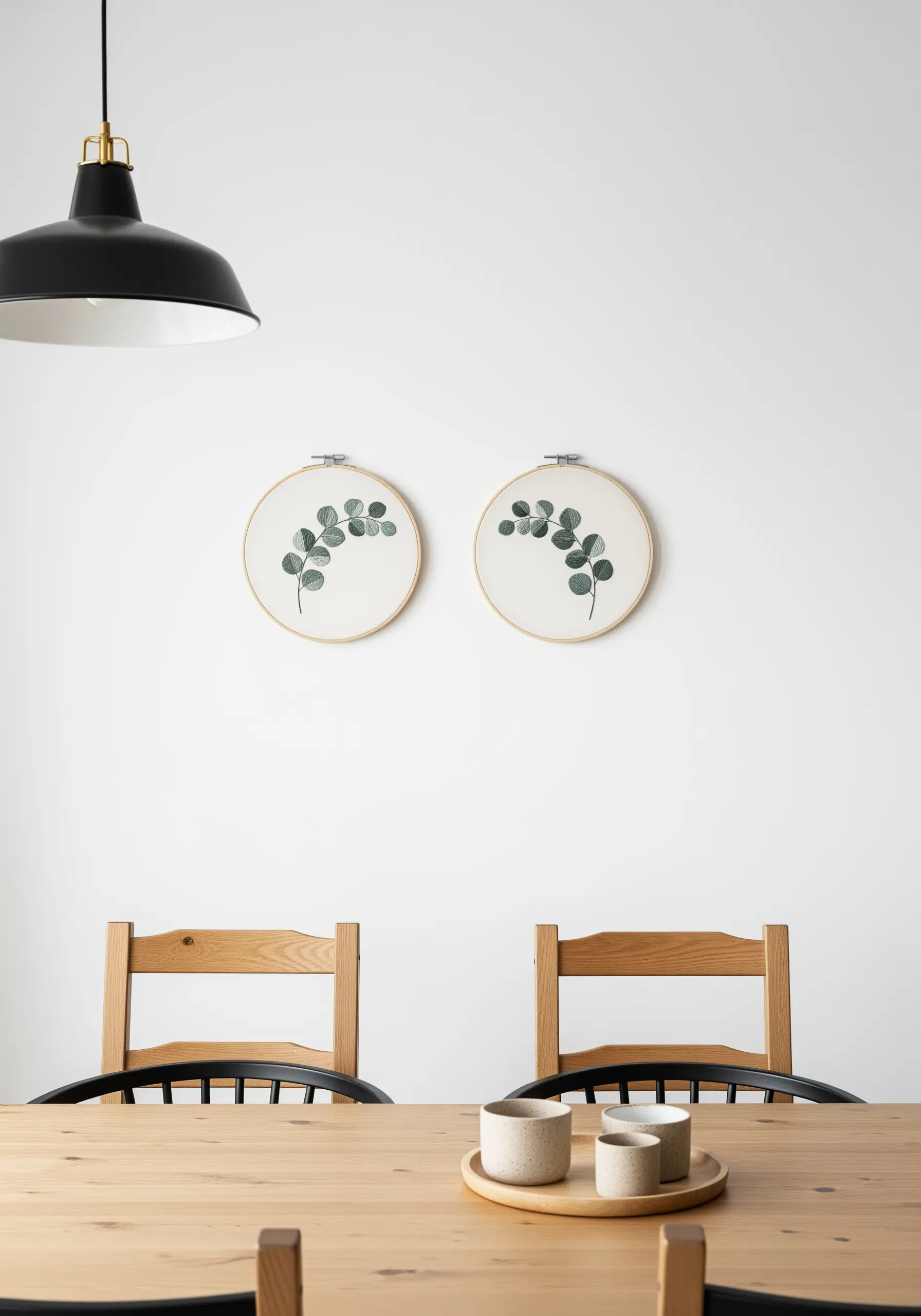 Two embroidery hoops with delicate eucalyptus branches stitched in a soft, painterly style.