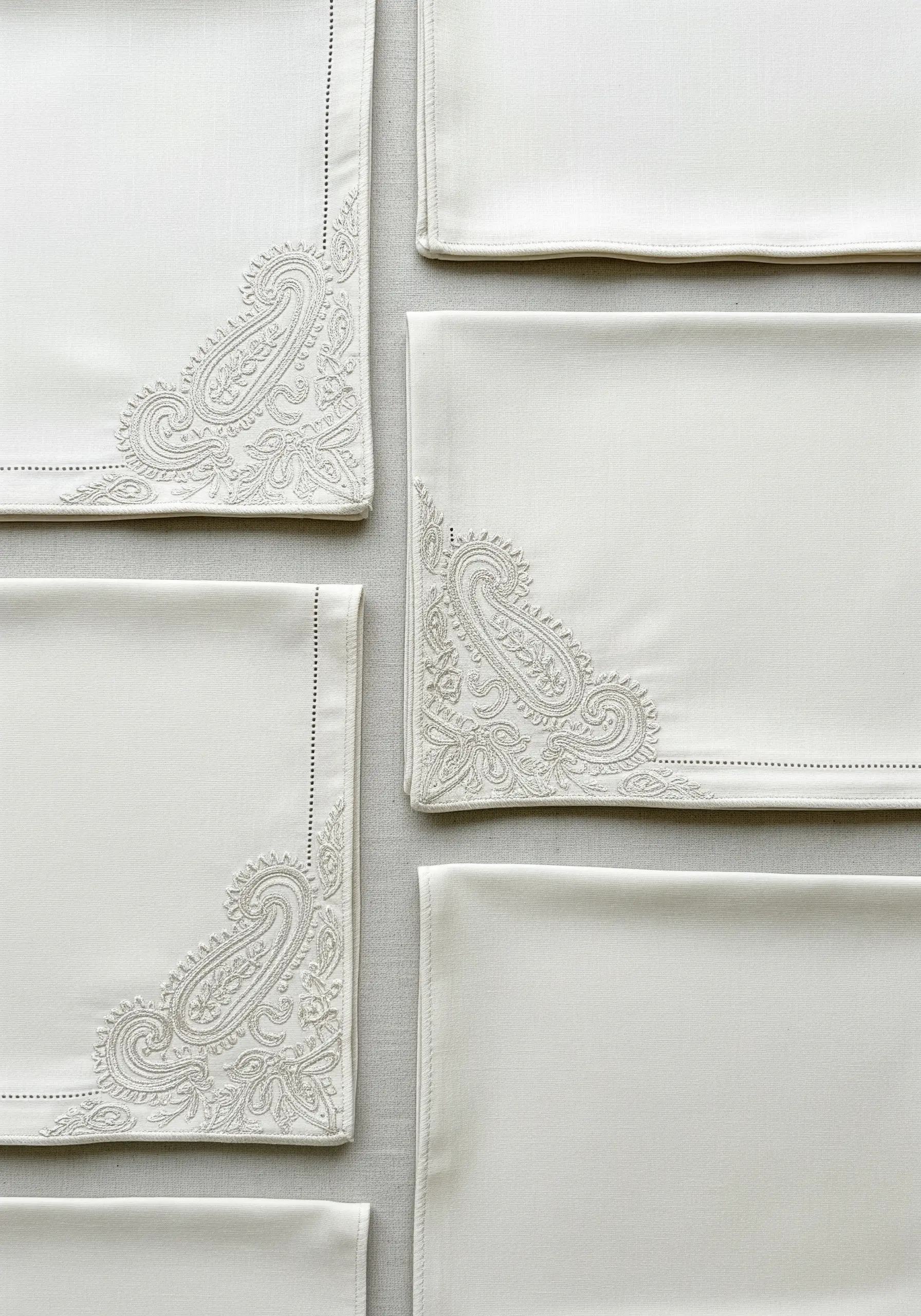 White placemats with elegant tone-on-tone paisley embroidery in the corners.