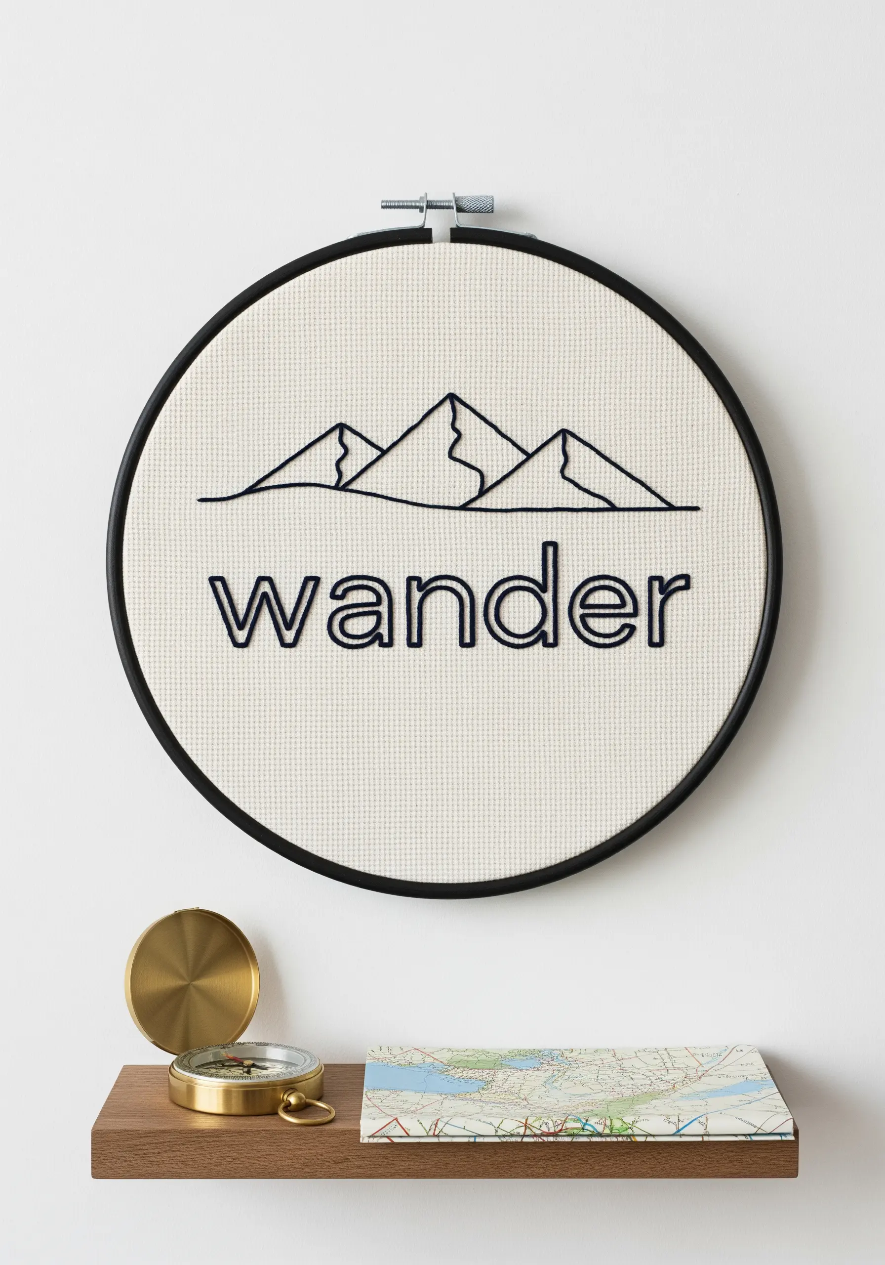 Line art mountain range above the word 'wander' embroidered in black on off-white fabric