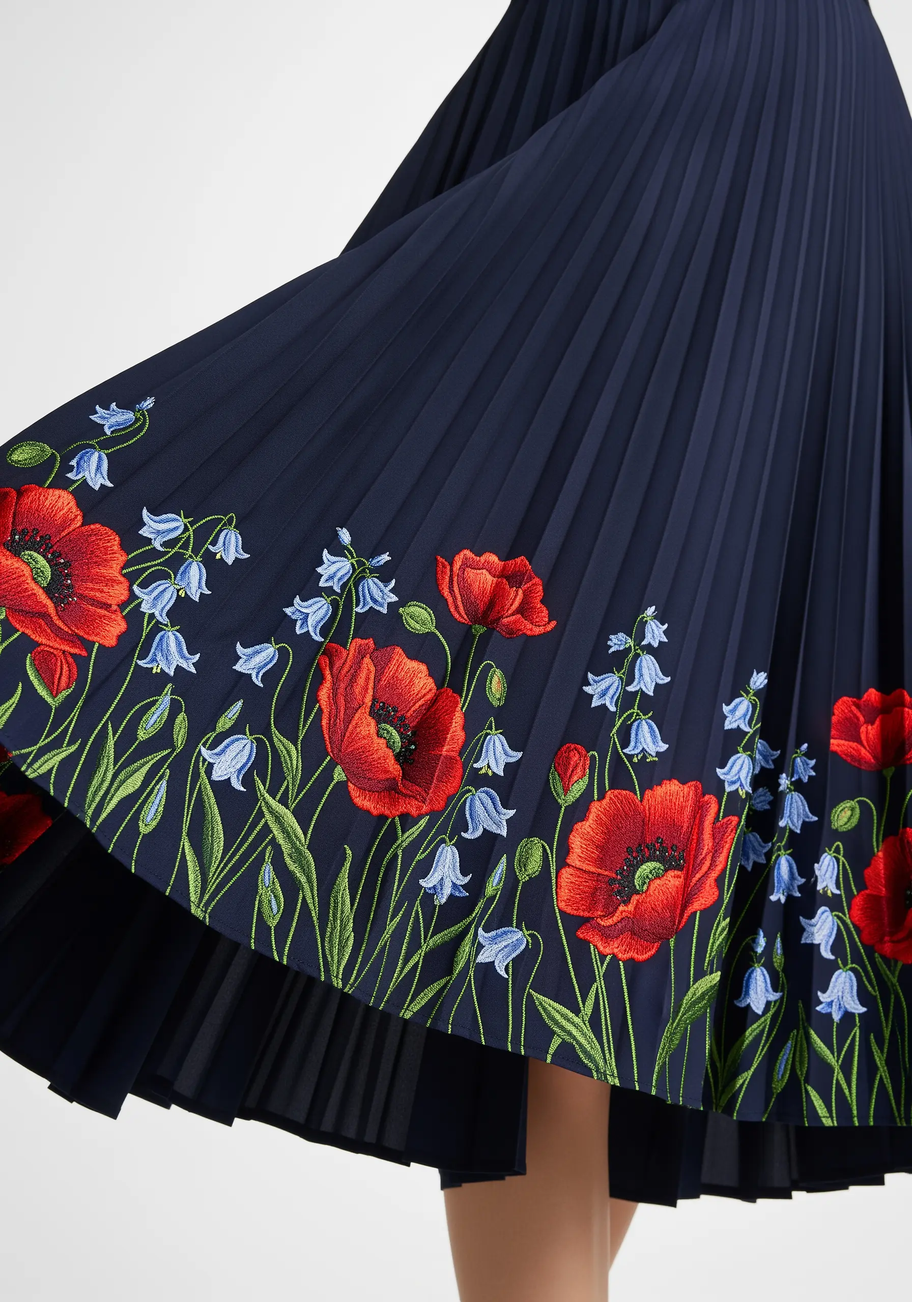 Vibrant red poppy and bluebell embroidery on the hem of a navy pleated skirt