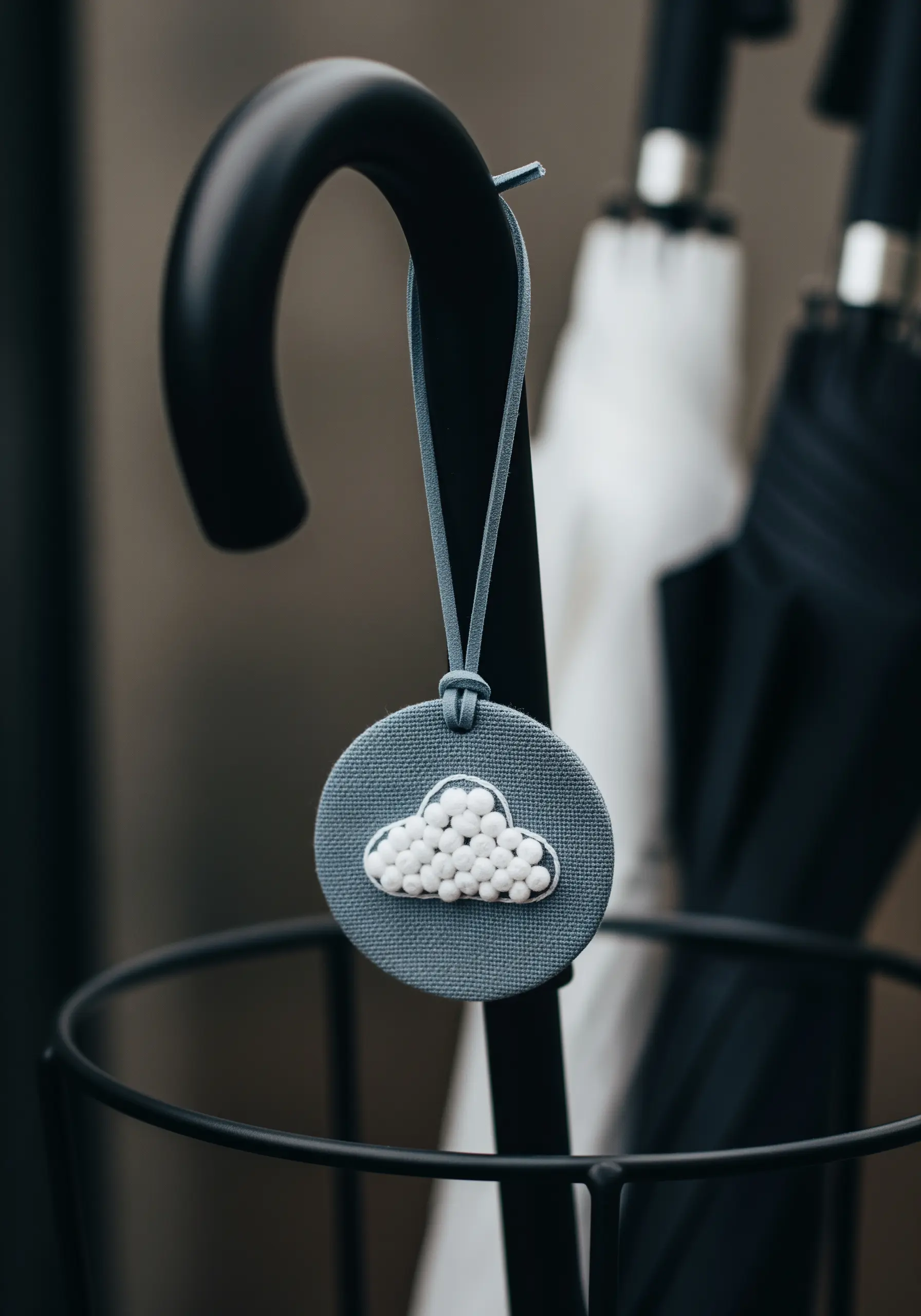 A small fabric charm with a cloud outline filled with tiny white beads.