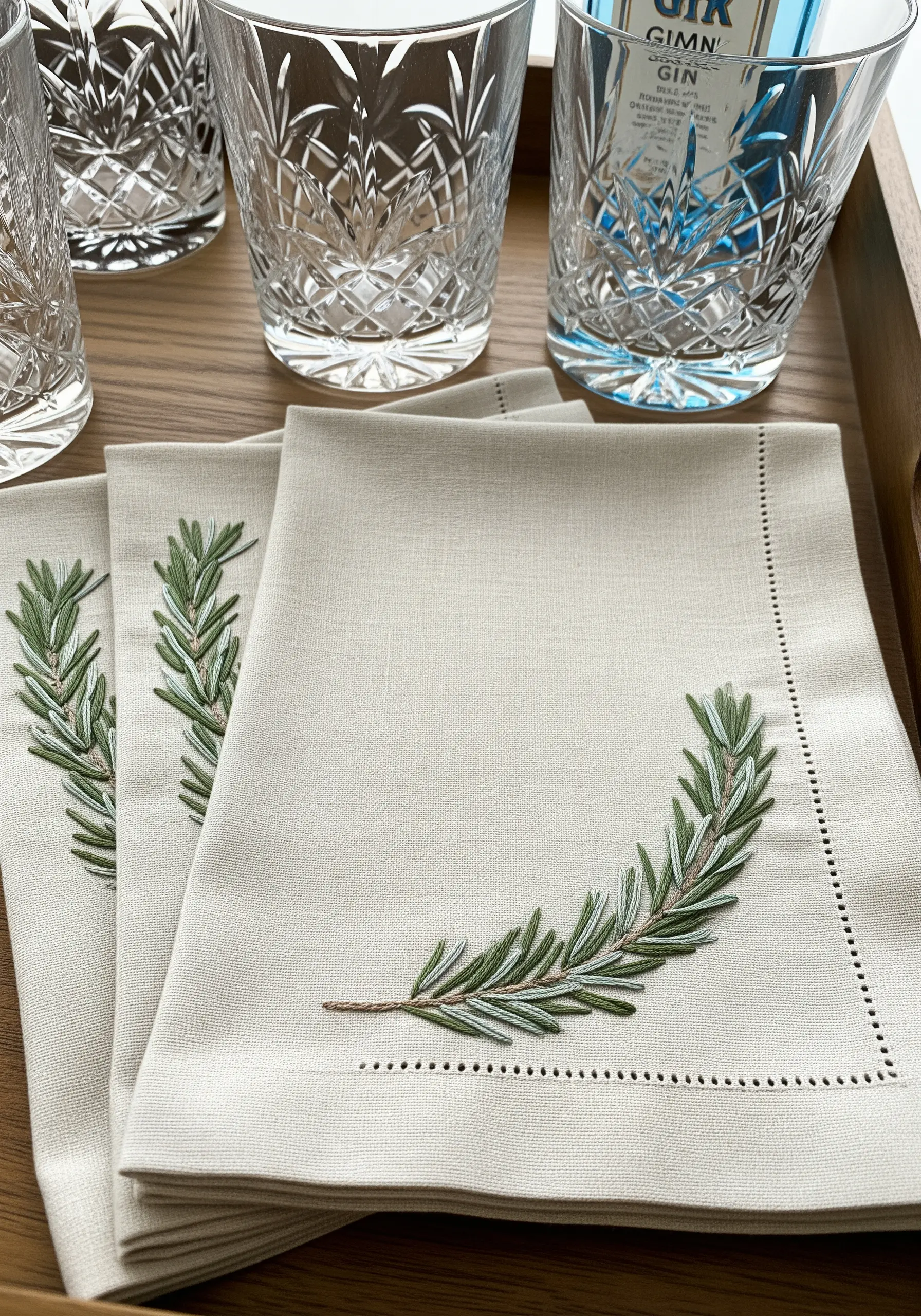 Linen napkins elegantly embroidered with a curved sprig of green rosemary.