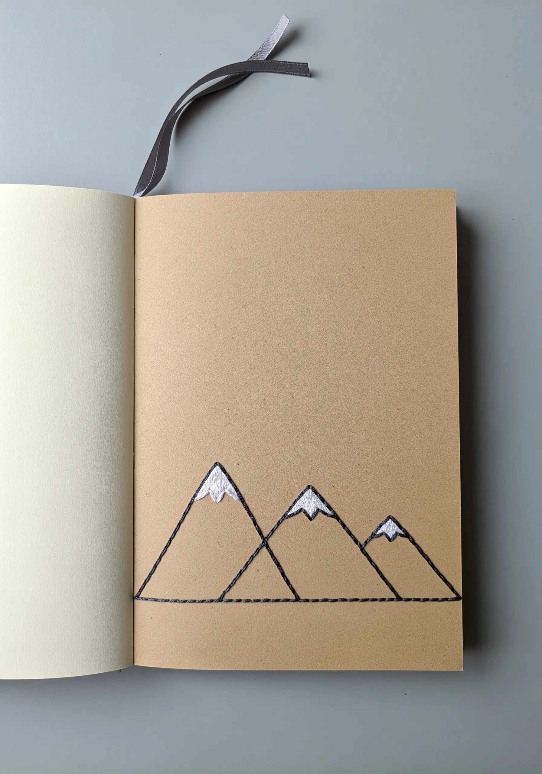 Minimalist line art embroidery of three mountains with white satin stitch snow caps.