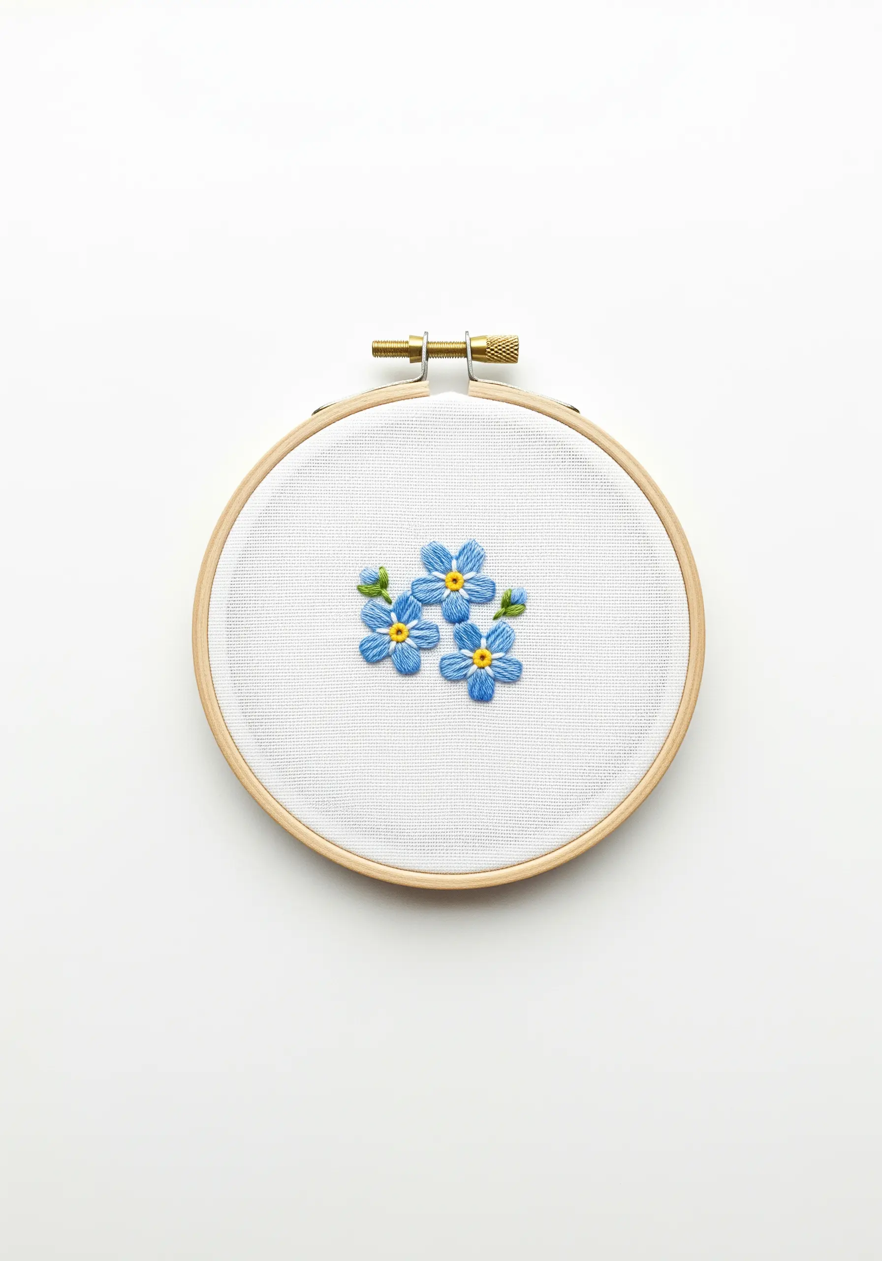 A trio of embroidered blue forget-me-not flowers in a small hoop.