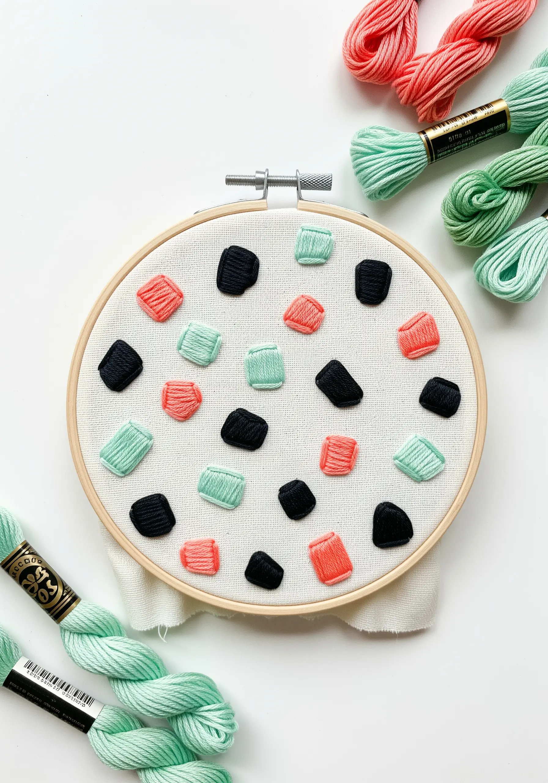Randomly scattered, puffy satin stitch shapes in mint, coral, and black.