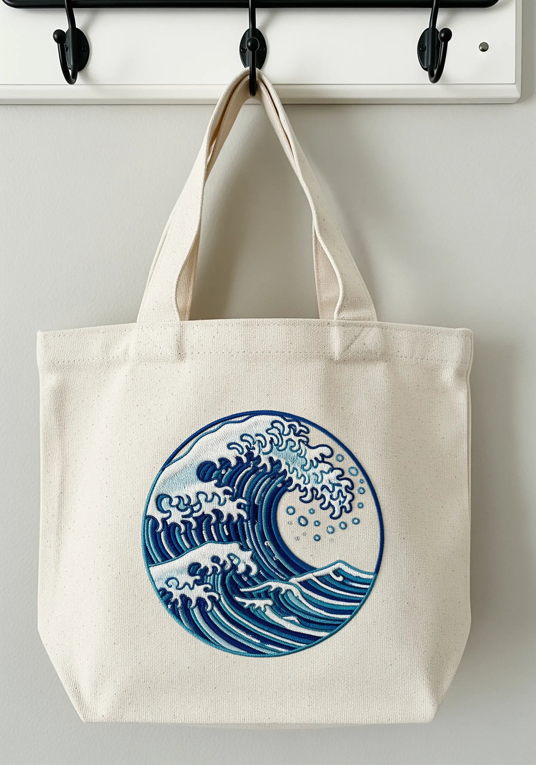 A canvas tote bag featuring a large, detailed embroidery of Hokusai's Great Wave.