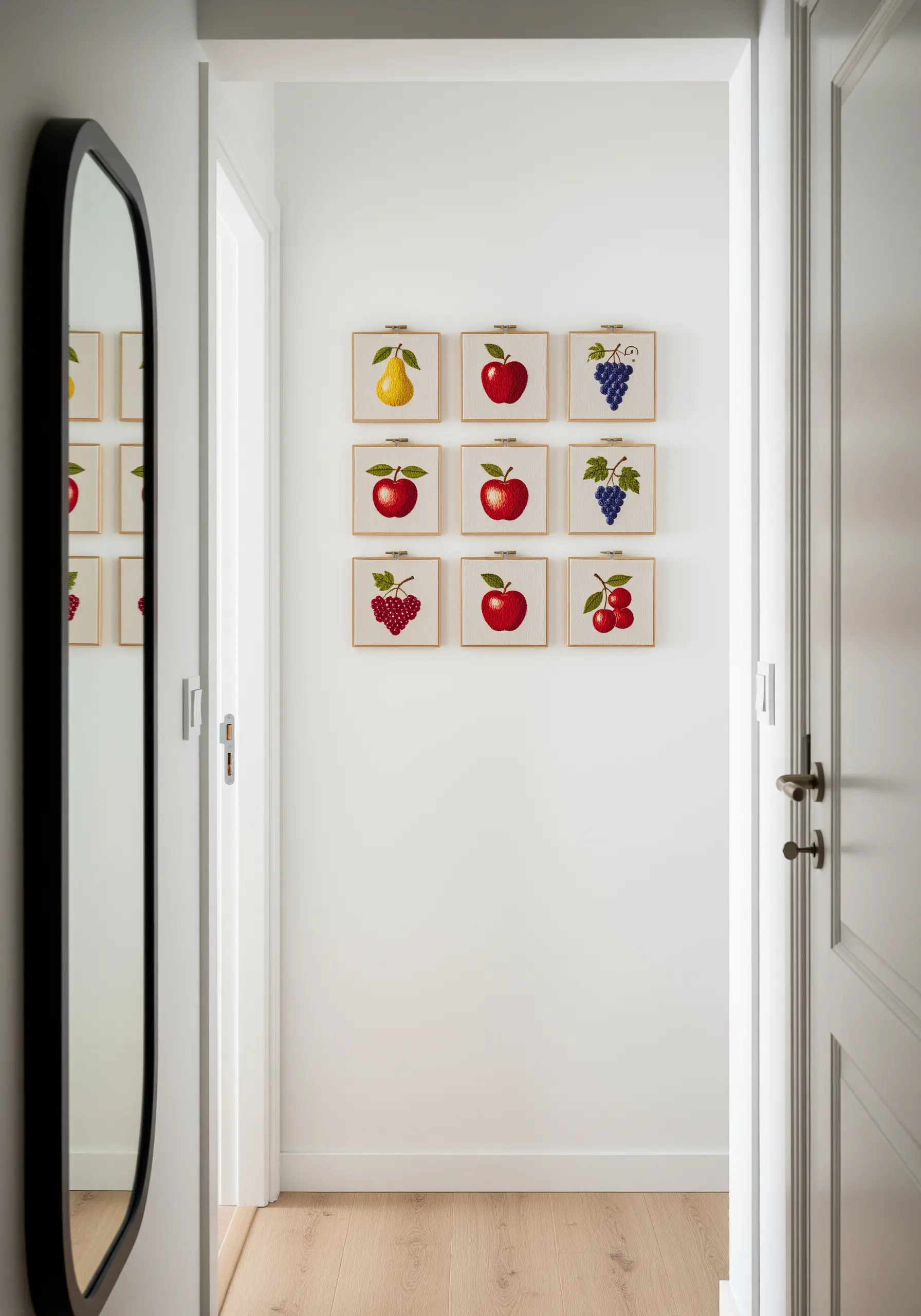 A nine-hoop grid displaying embroidered fruit motifs on a clean white hallway wall.