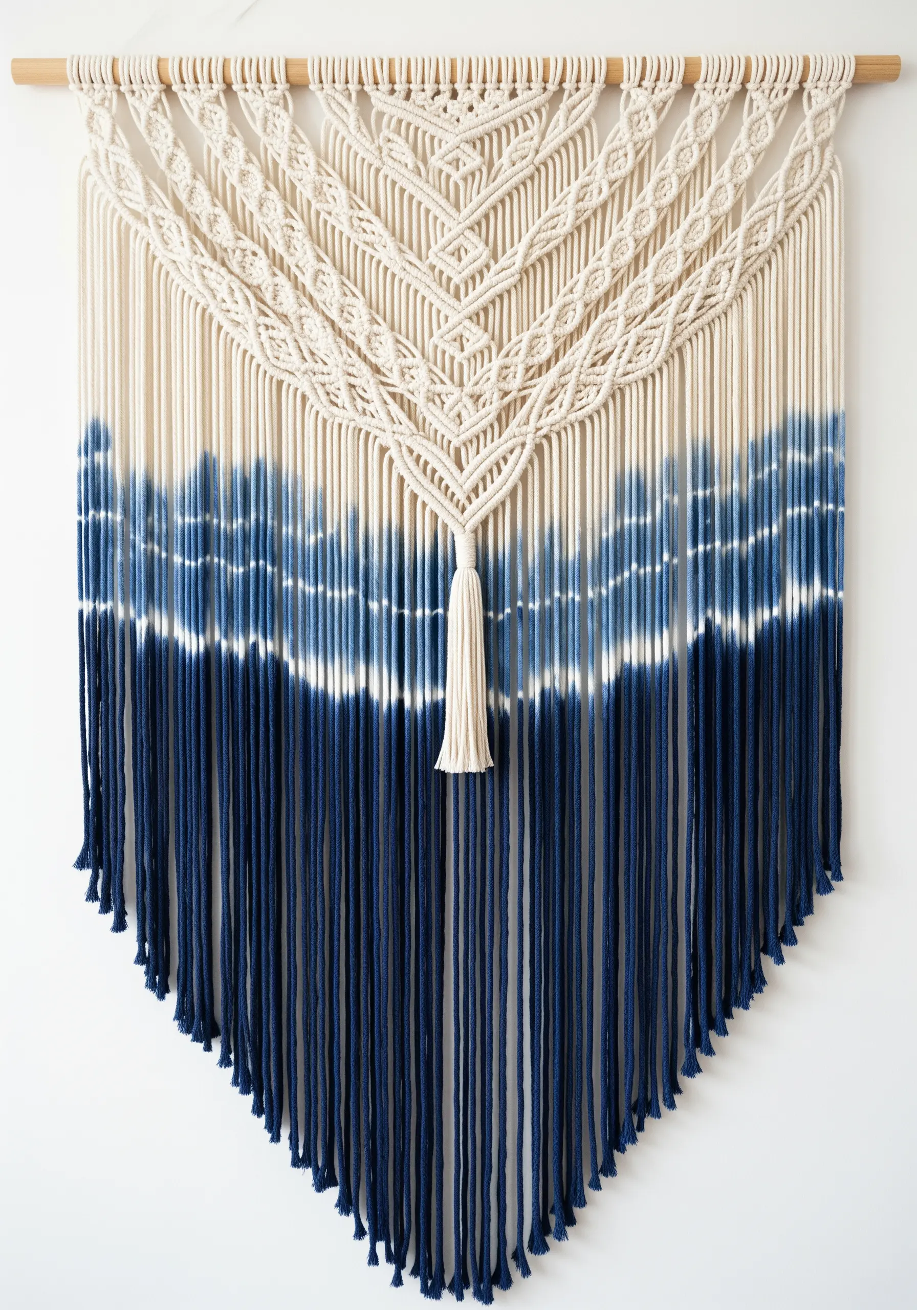 A large macrame wall hanging with the bottom half dip-dyed in shades of indigo blue.