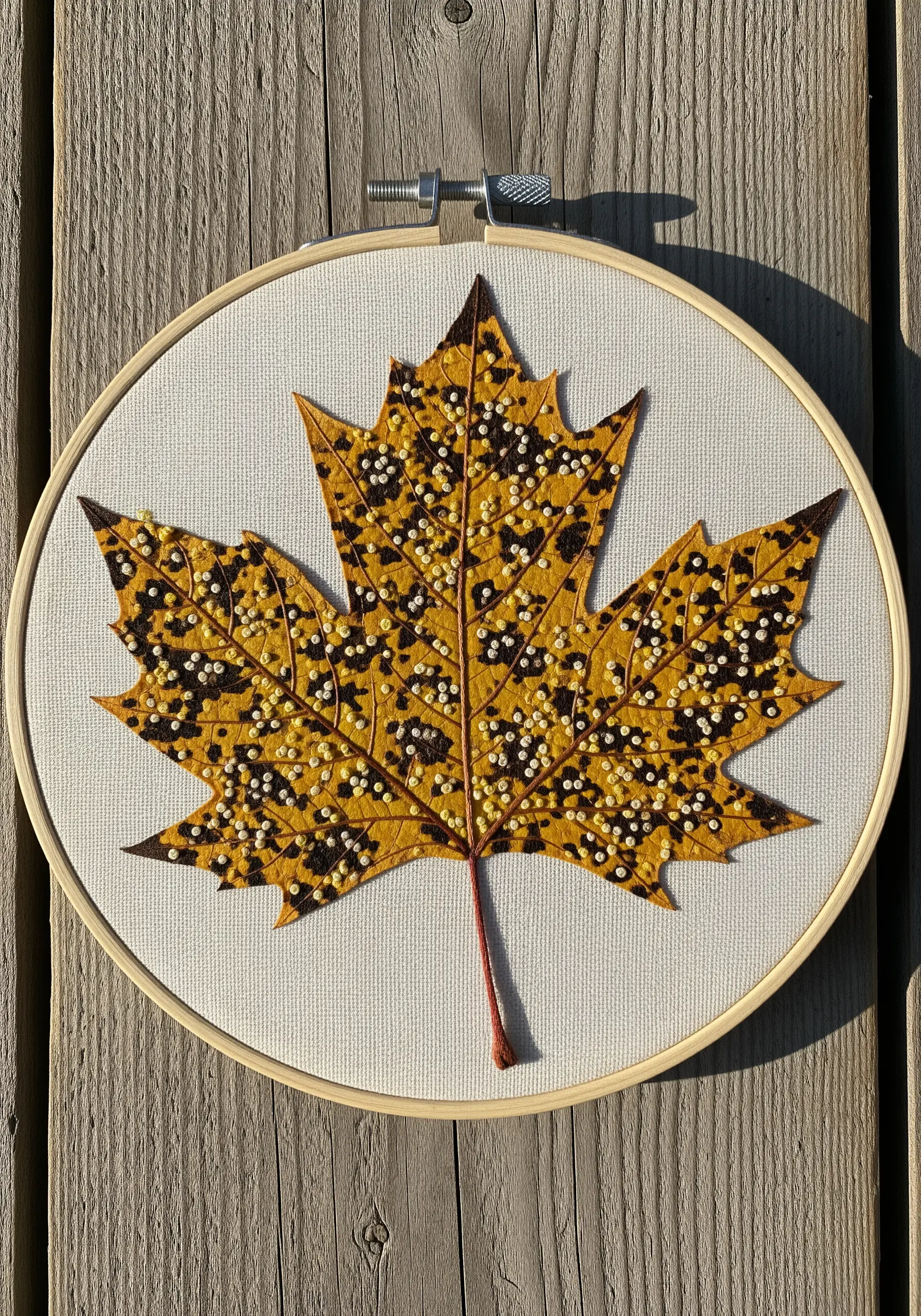 A yellow maple leaf appliqué embellished with black and white beads for a spotted effect.