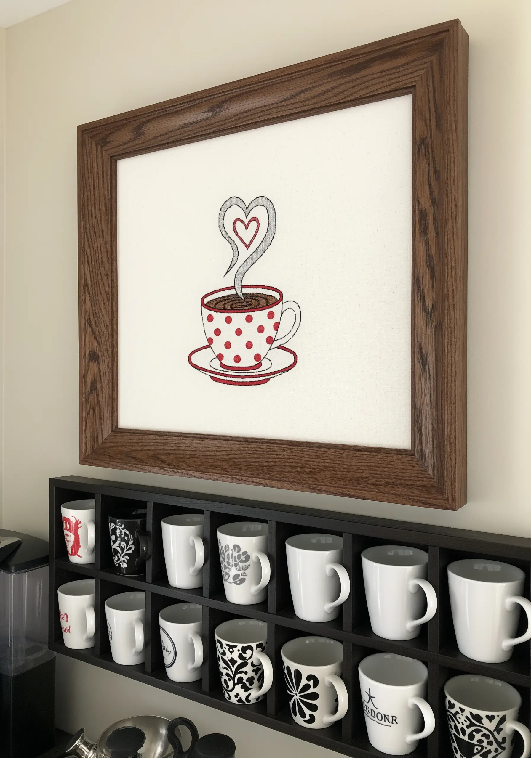 Embroidery of a red and white polka dot coffee cup with a heart in the steam.