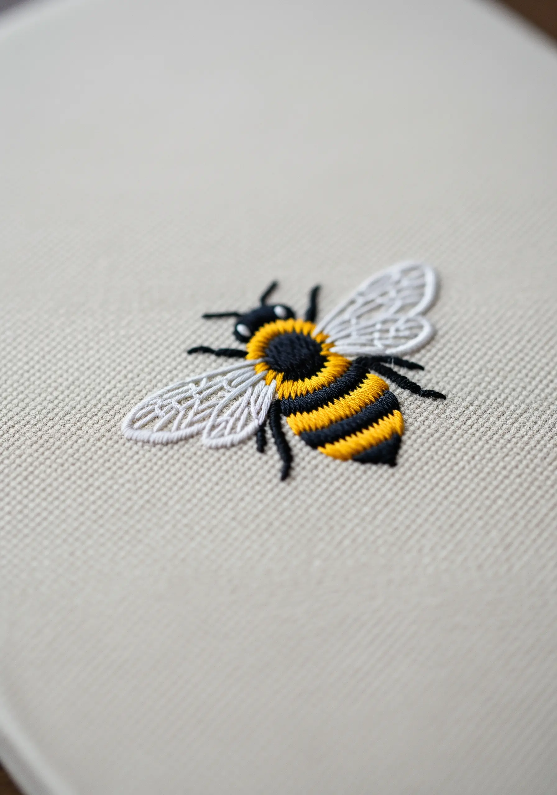 Detailed embroidery of a bee, with delicate, veined stitches for the wings.