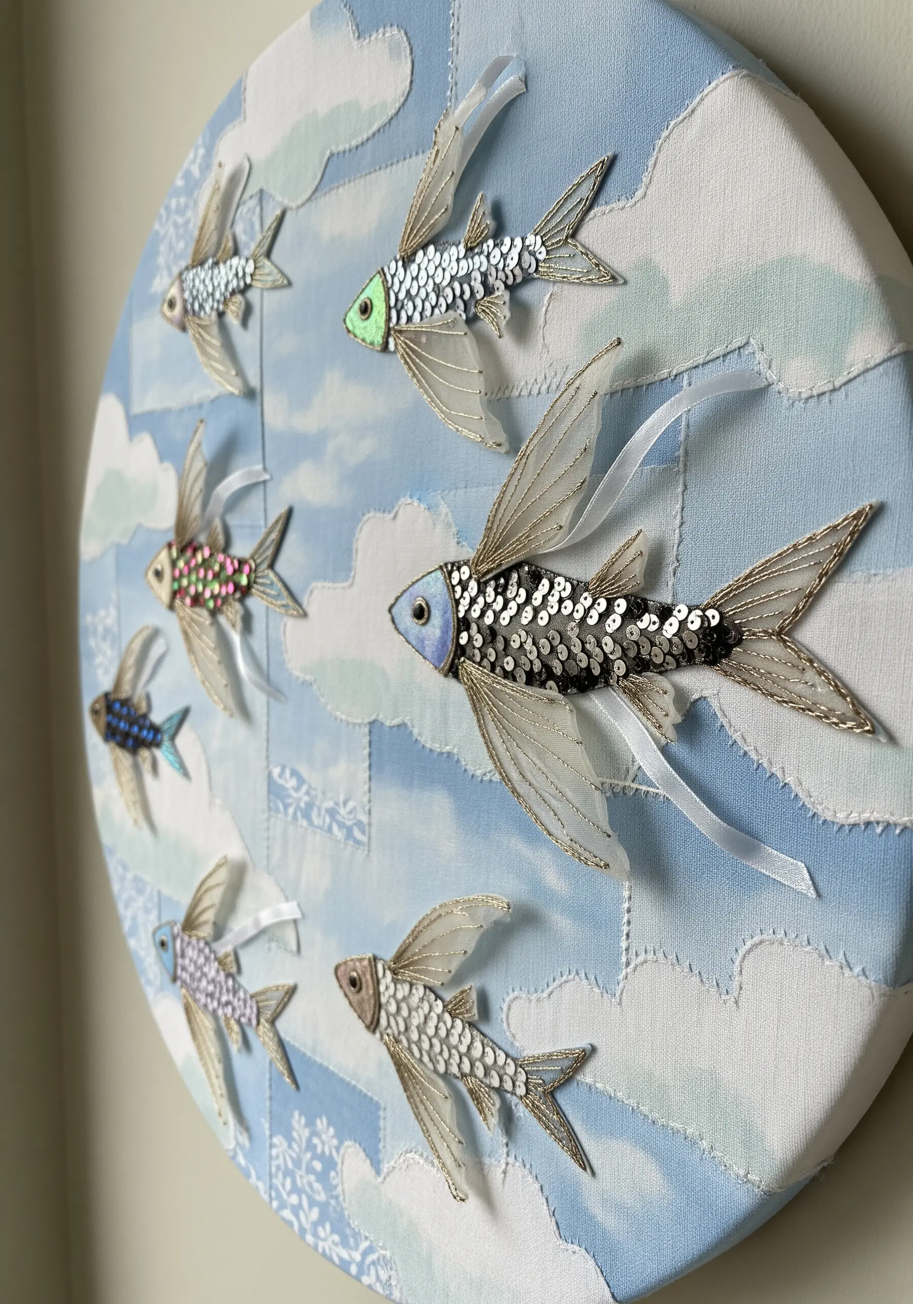 Fabric collage of flying fish made with sequined fabric bodies and organza fins