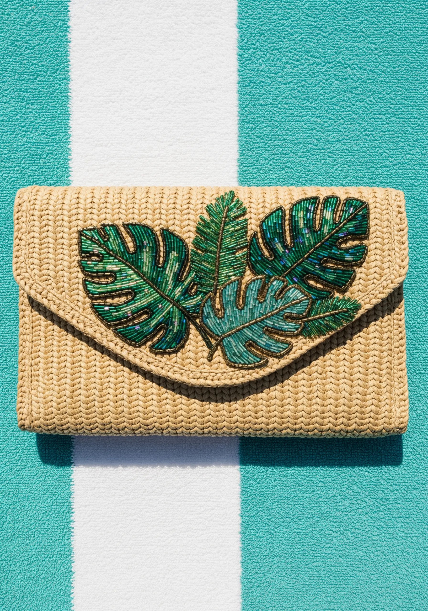 Tropical leaves on a straw clutch intricately filled with green and teal seed beads.