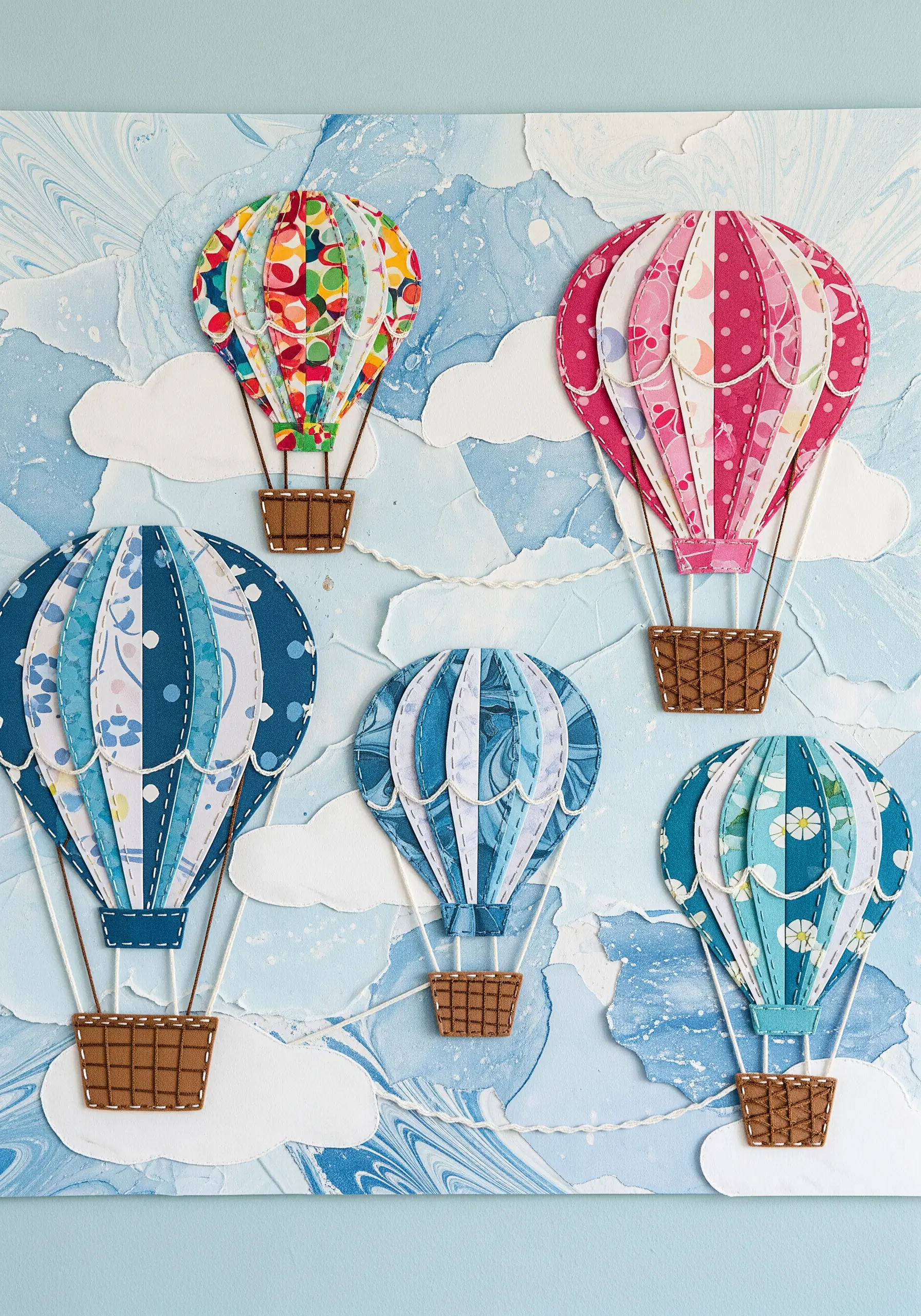 Paper collage hot air balloons with running stitches on the seams and satin-stitched baskets.