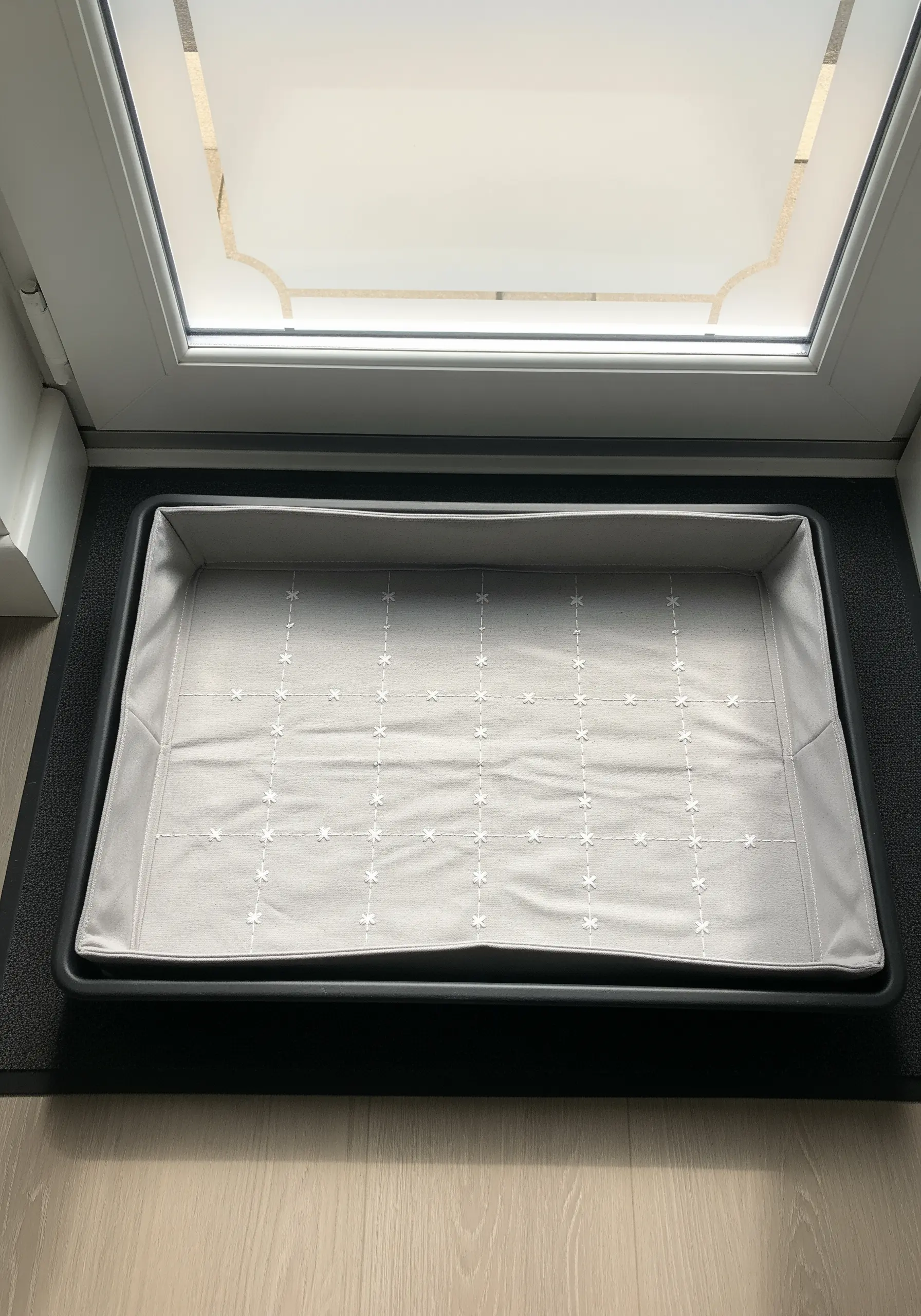 A grid of small, white star stitches on a grey fabric boot tray liner.