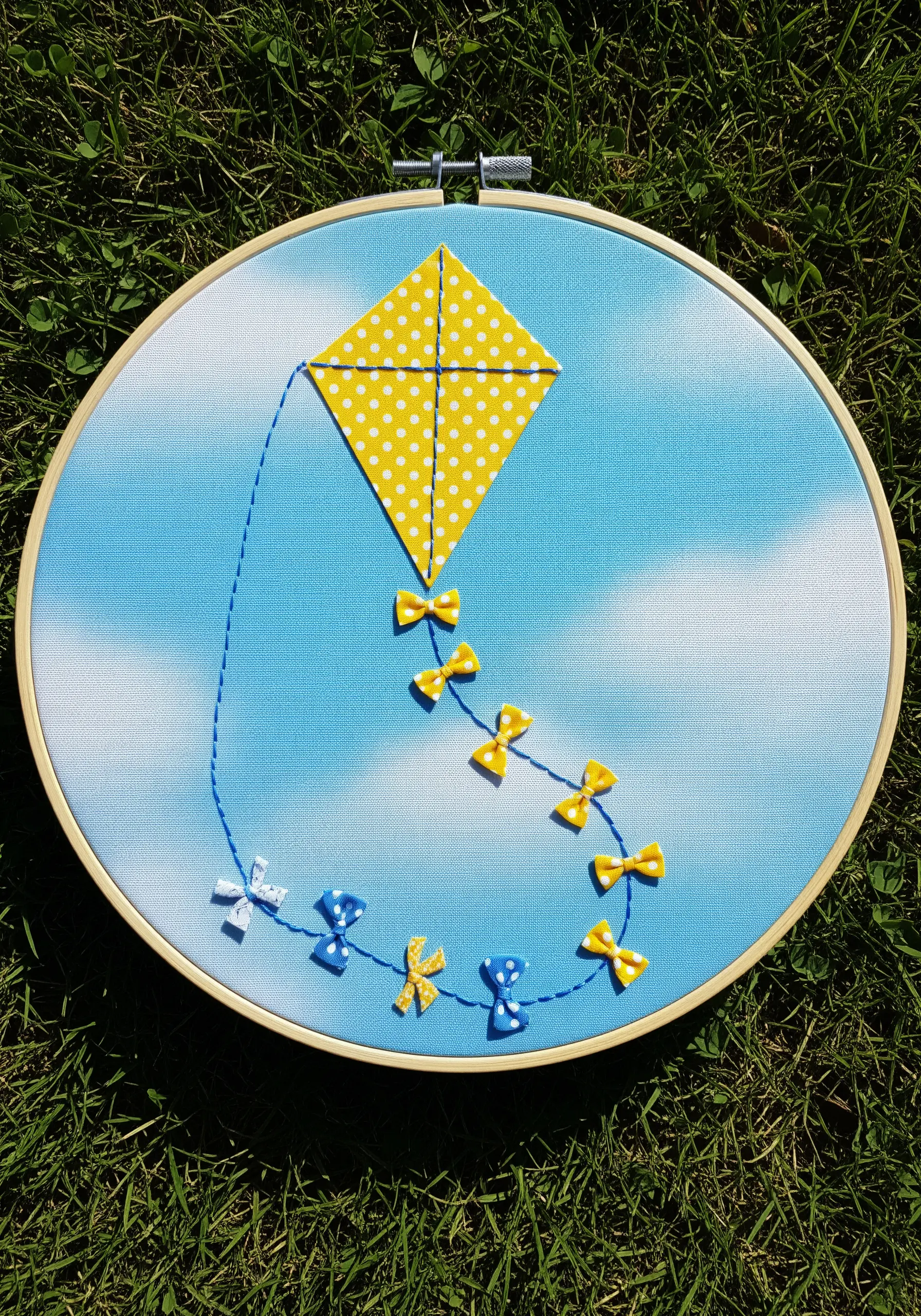 A yellow polka-dot fabric kite with a tail made of tiny ribbon bows.