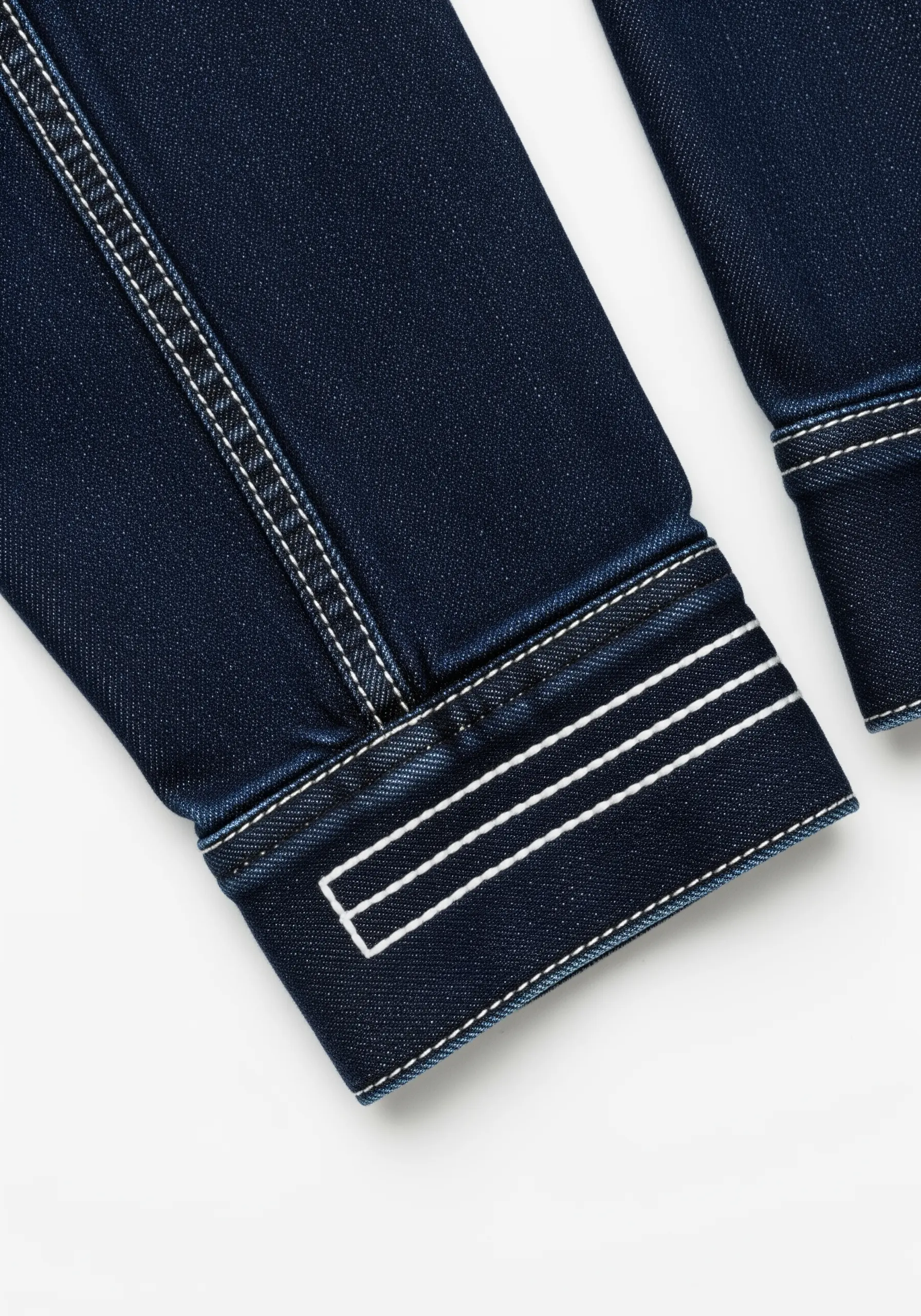 Clean, parallel lines of white thread stitched onto the cuff of a dark denim jacket.