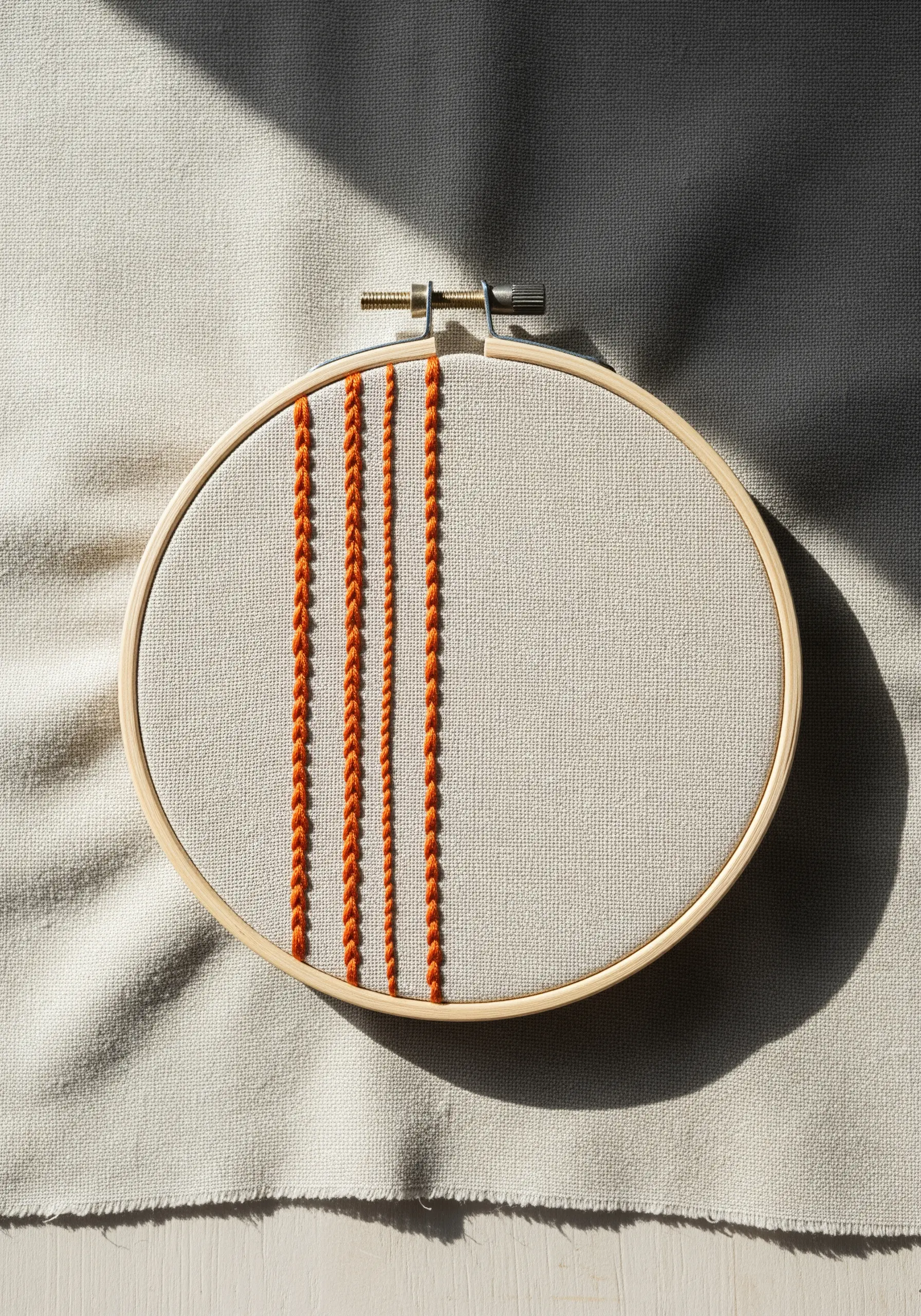 Four vertical lines in orange thread, showcasing different embroidery stitches.