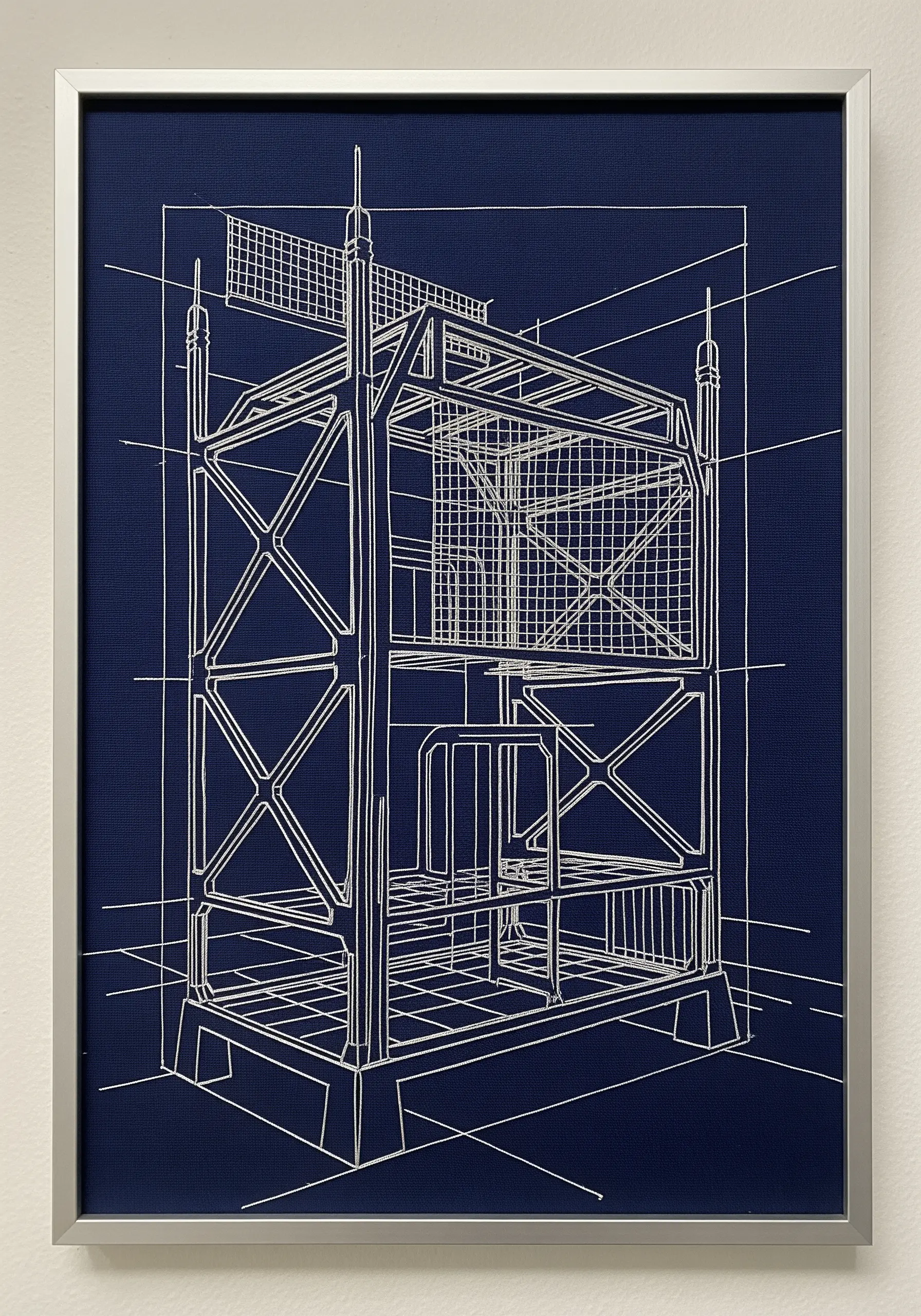 White thread embroidery of an architectural blueprint on a dark blue background, framed.