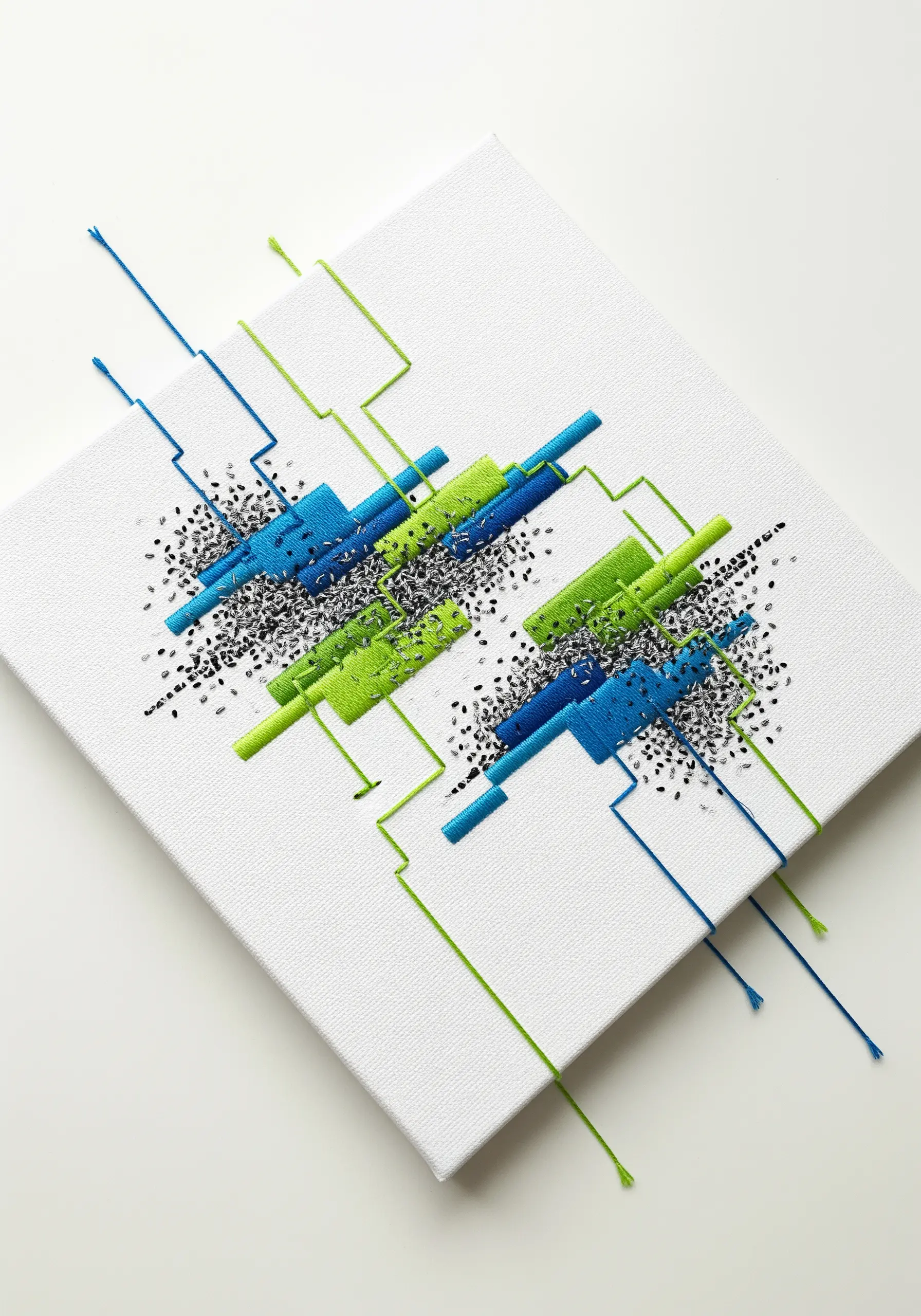 Geometric satin stitch blocks on a white canvas with threads extending beyond the shapes.