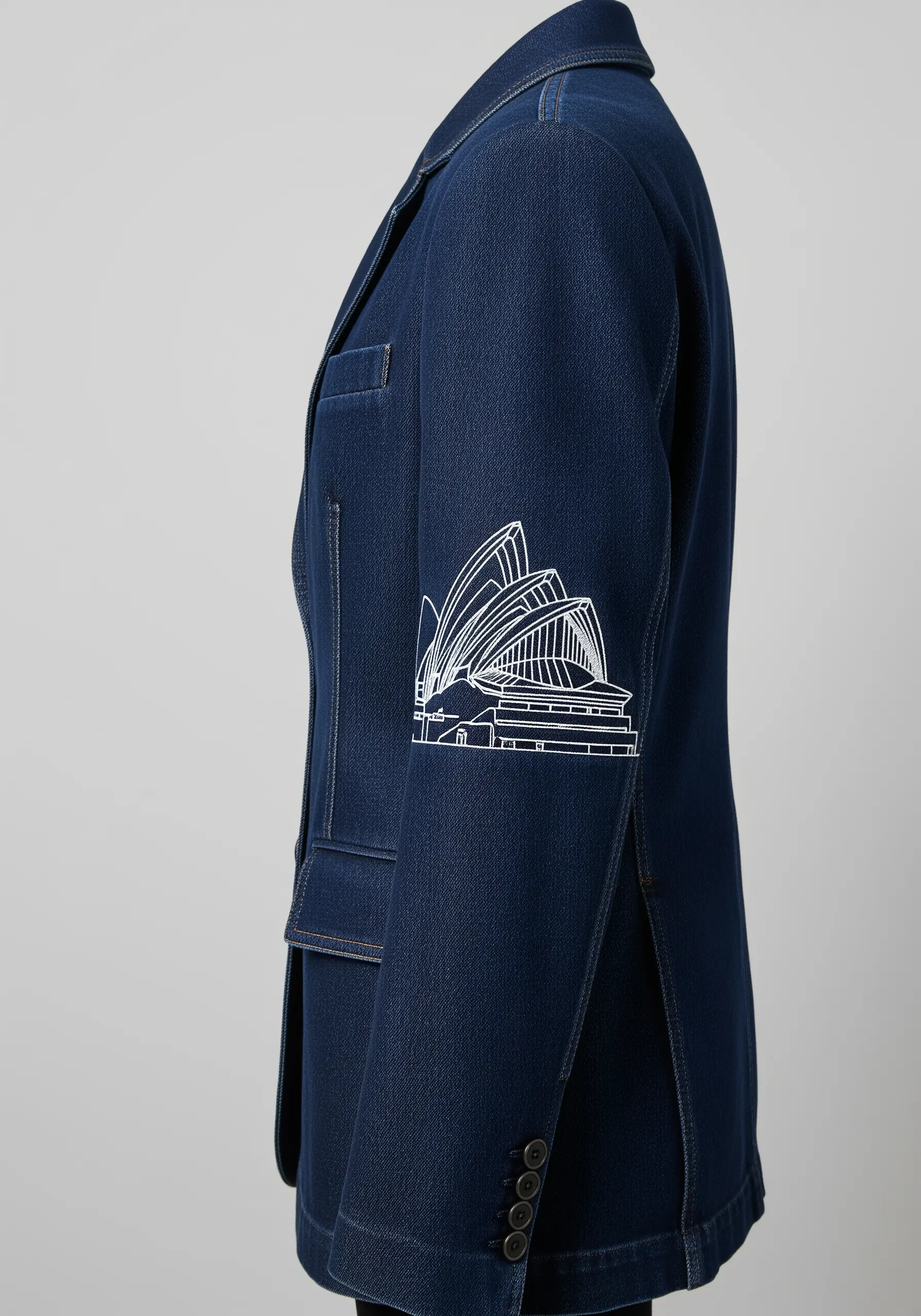 Minimalist line art embroidery of the Sydney Opera House on a denim jacket sleeve.