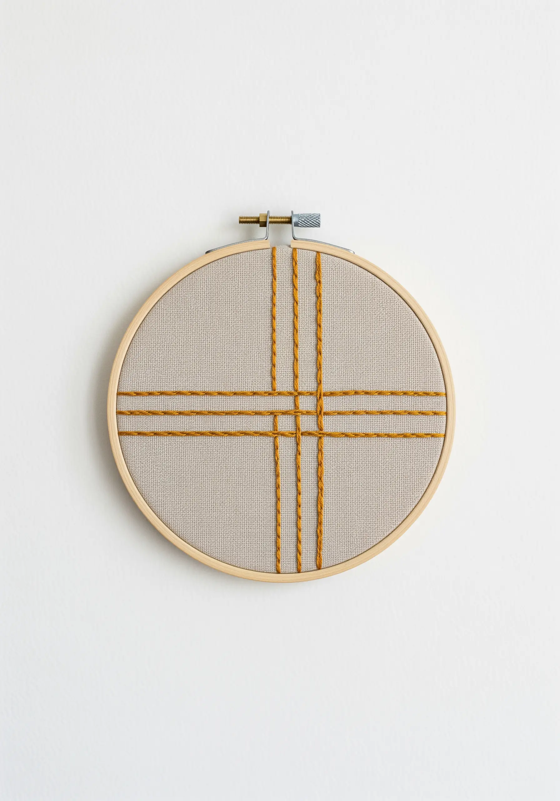 Minimalist geometric embroidery with intersecting mustard yellow lines in a wooden hoop.