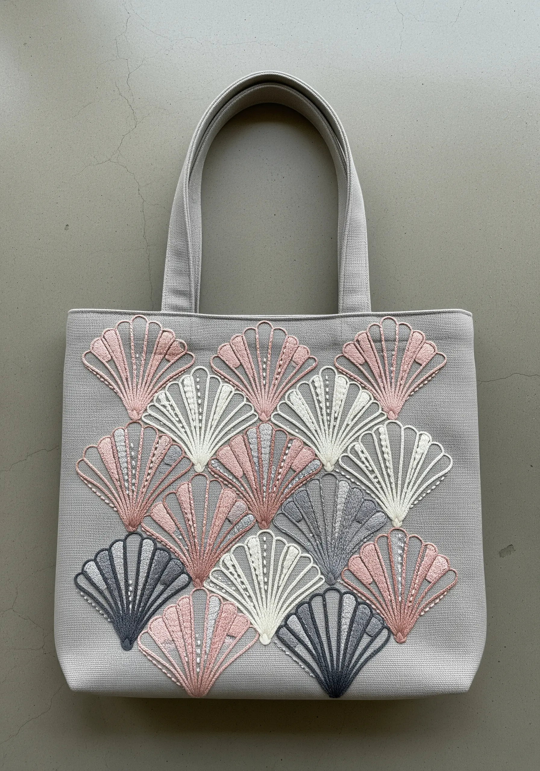 A repeating pattern of embroidered art deco style shells in pink, grey, and white.