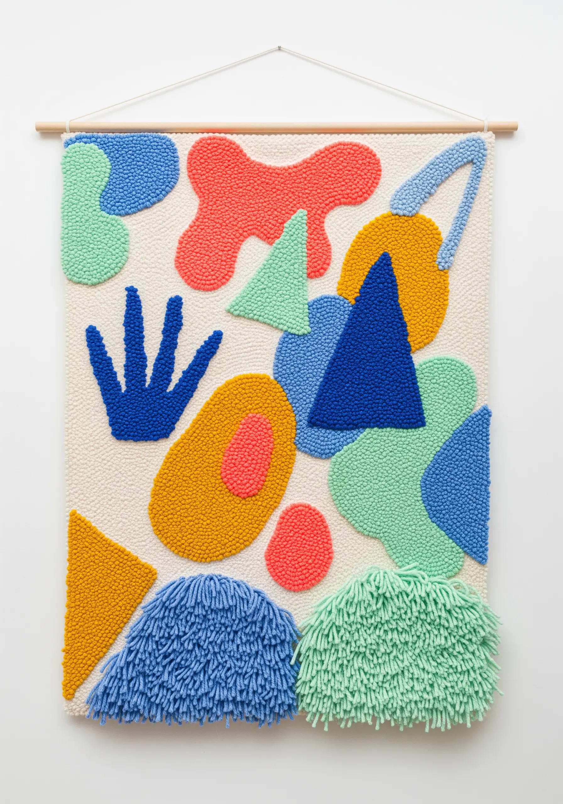 A large punch needle wall hanging with abstract, colorful shapes in blue, green, yellow, and coral.
