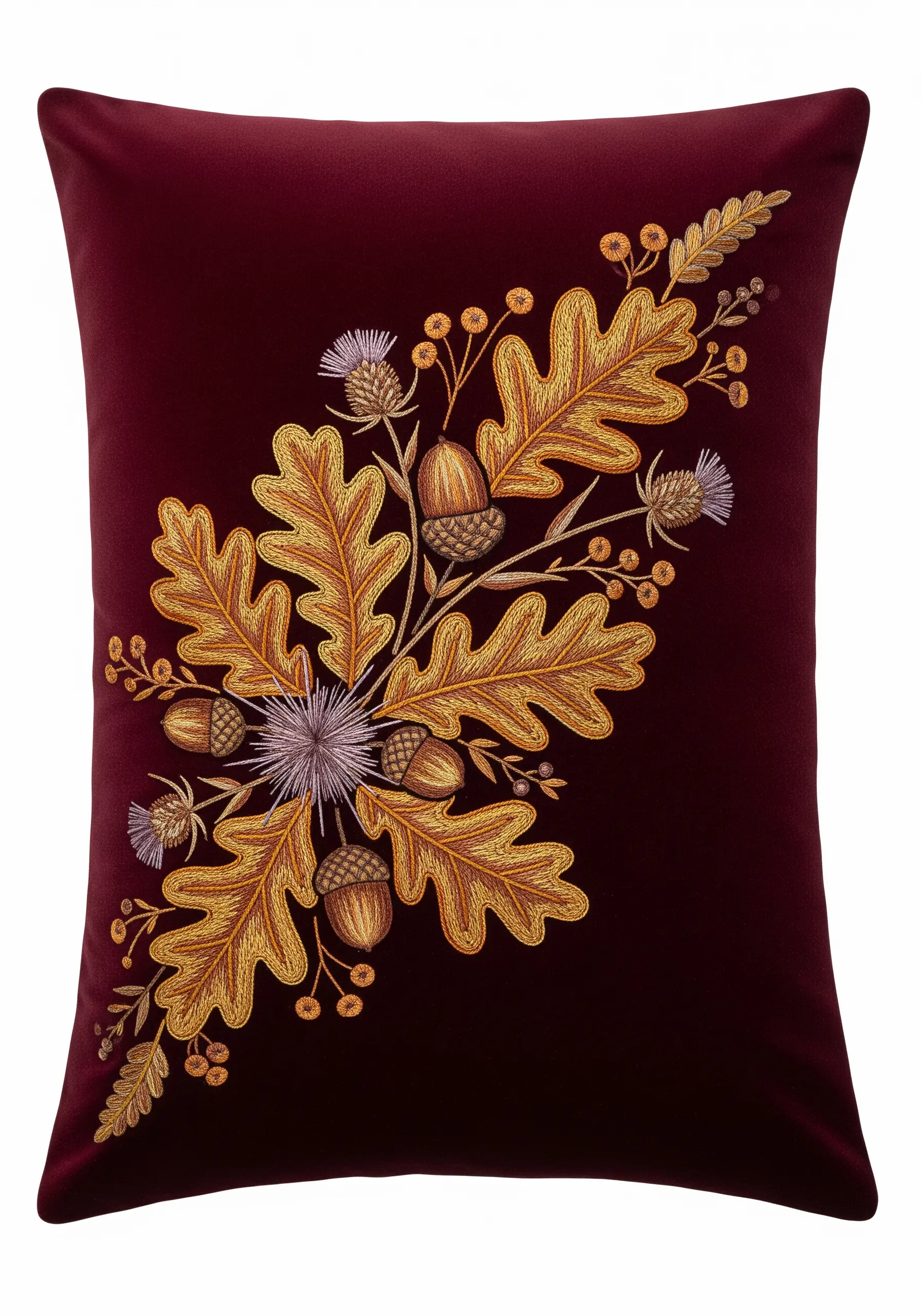 An autumnal bouquet of embroidered oak leaves and acorns on a rich burgundy pillow.