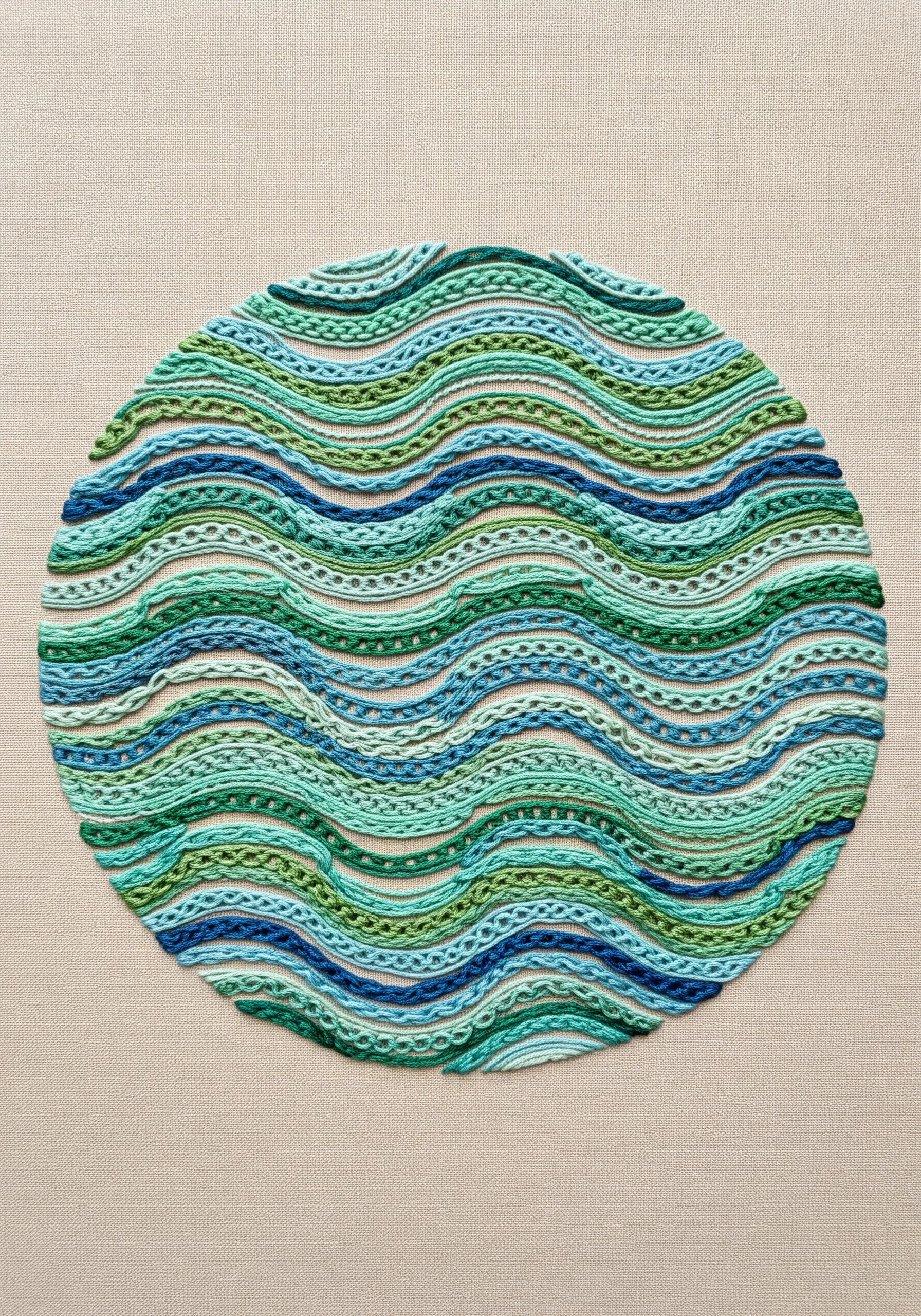 A circular embroidery with wavy horizontal bands of various green and blue stitches.
