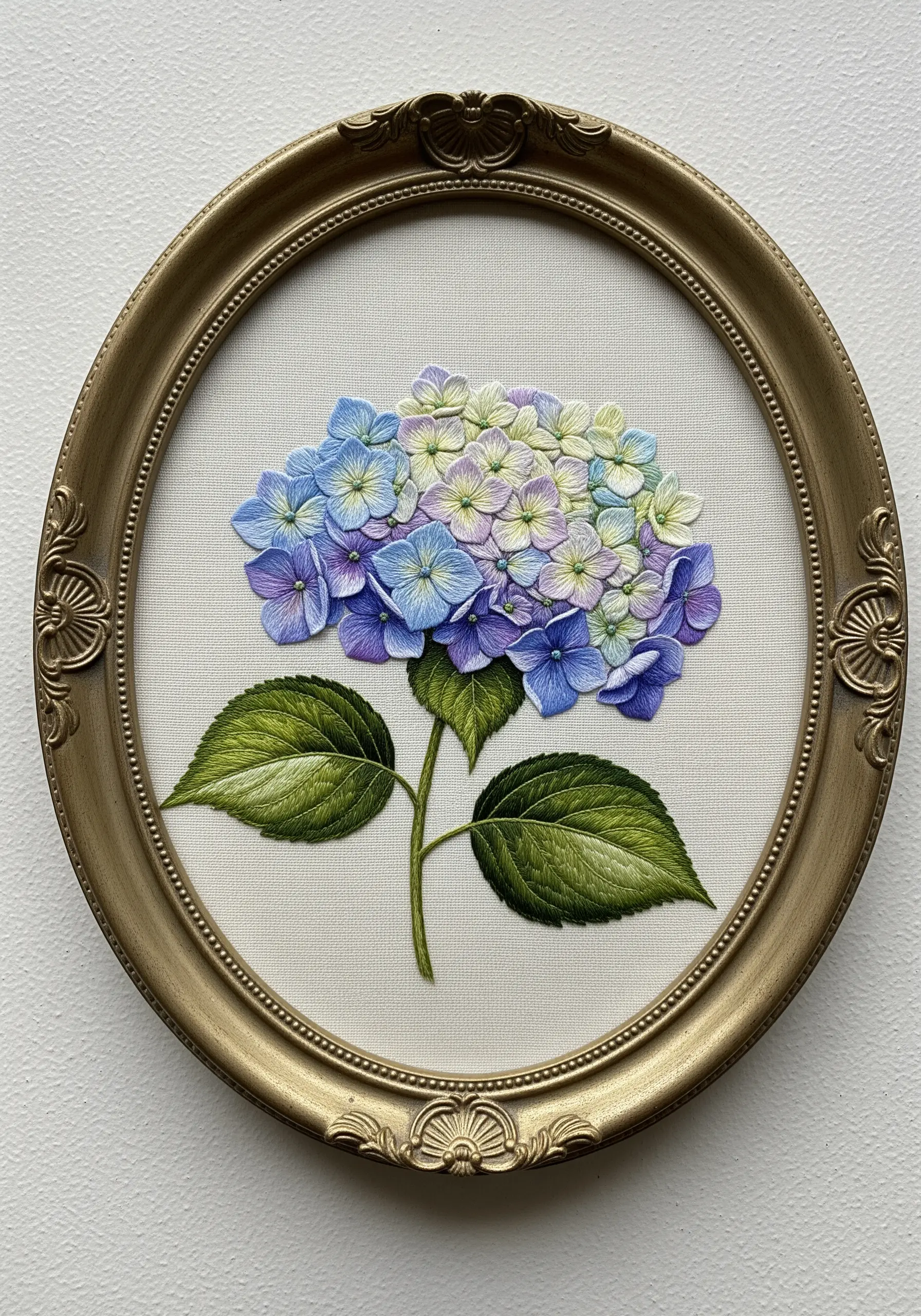 A realistic hydrangea blending pale green, blue, and violet, displayed in an oval gold frame.