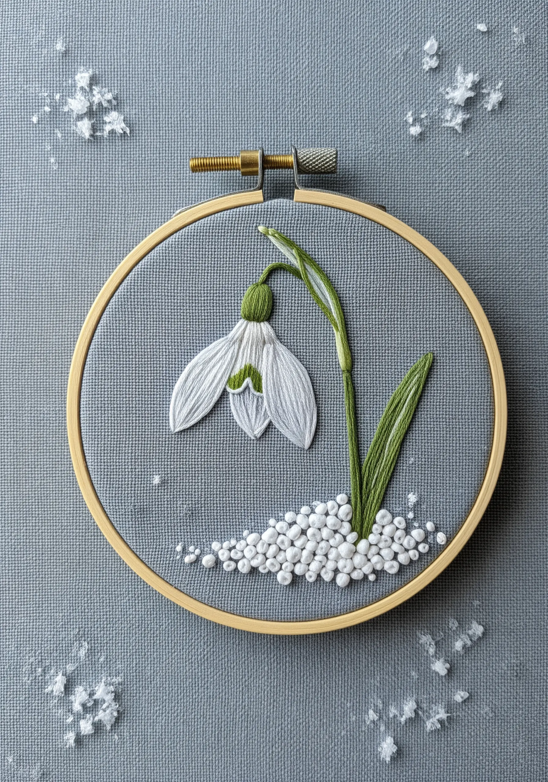A single snowdrop flower embroidered with thread-painted petals and beaded snow
