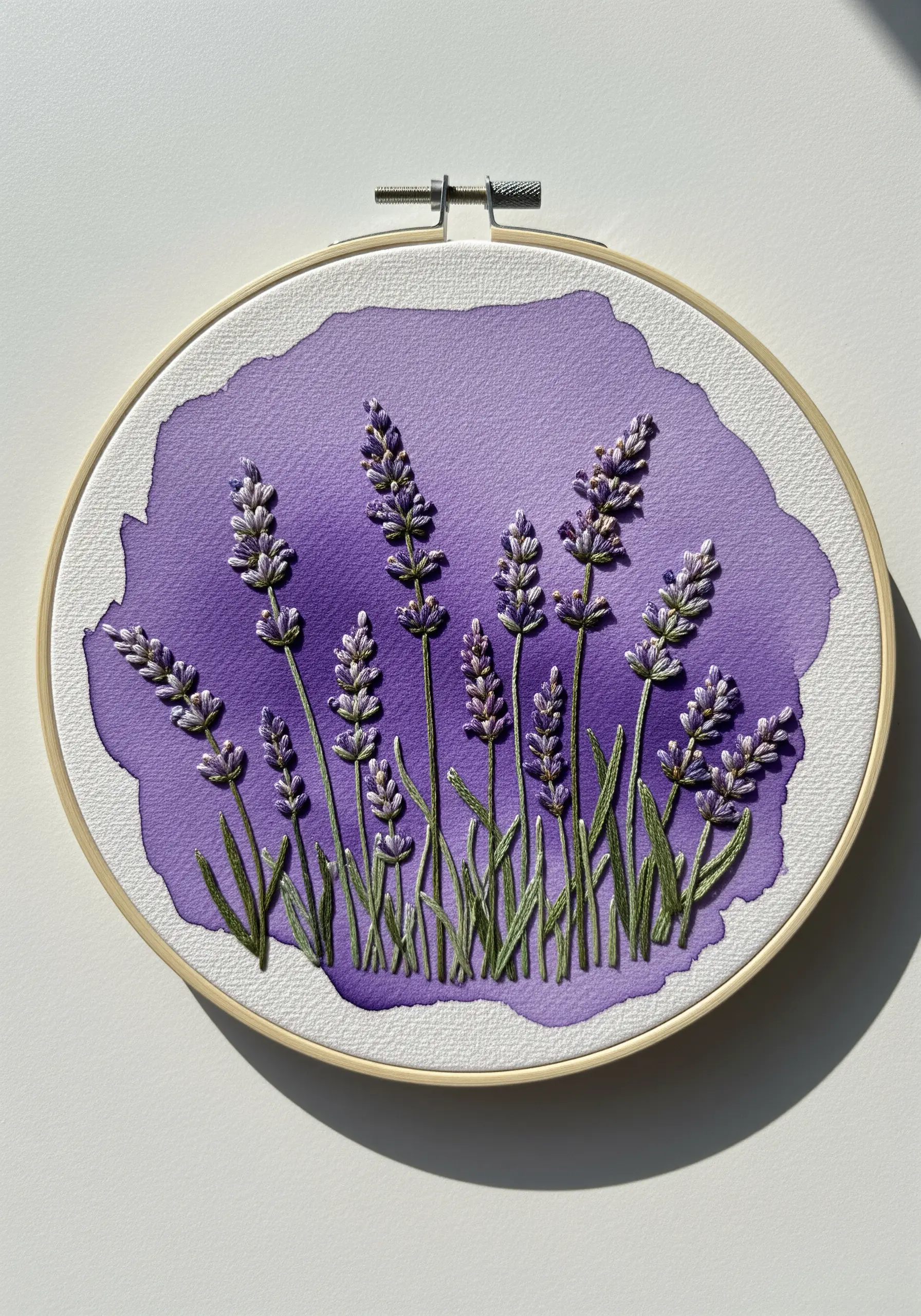 Lavender stems embroidered over a purple watercolor wash background in a hoop.