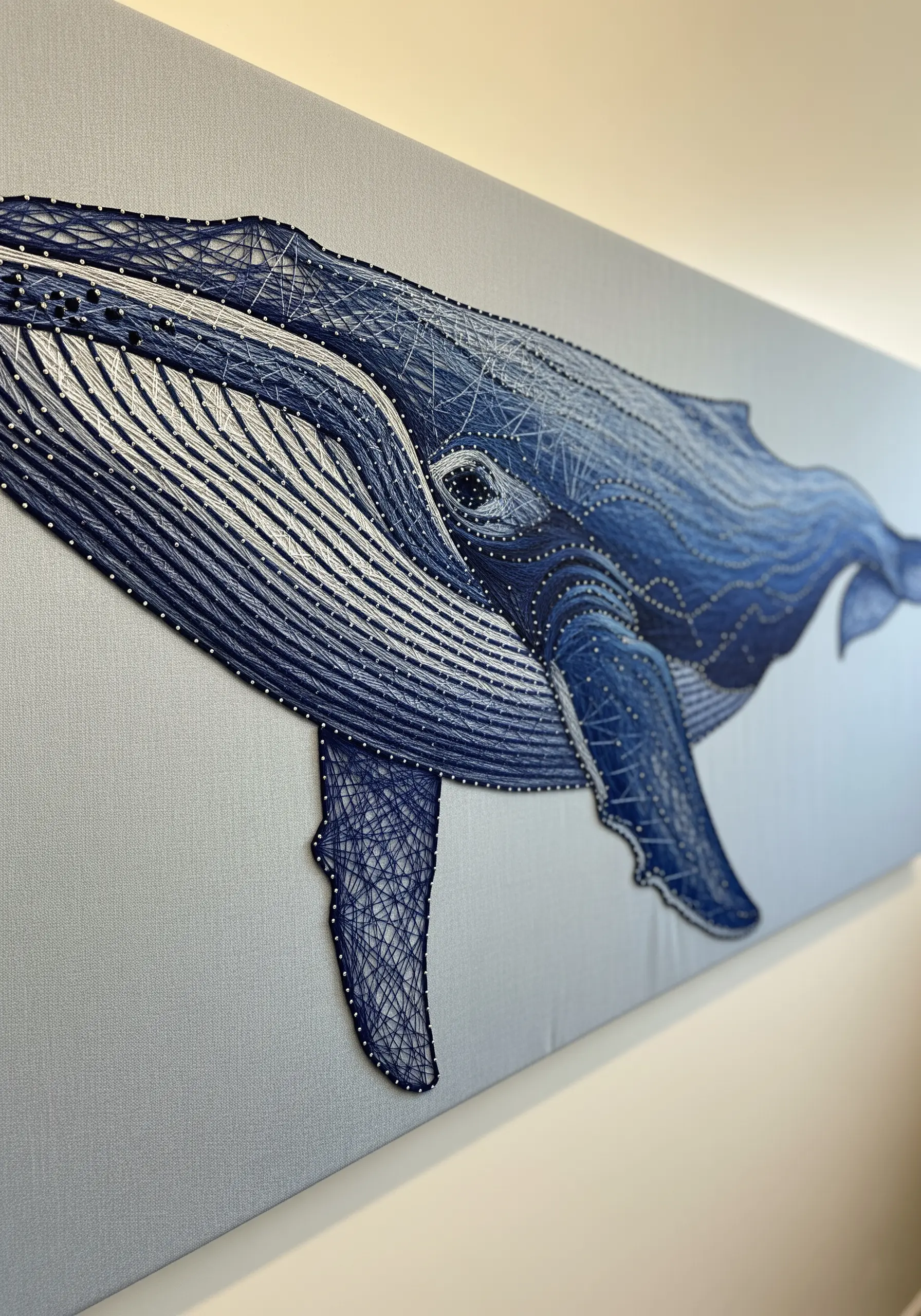 Large string art whale on a light gray canvas, using blended blue and white threads for depth.