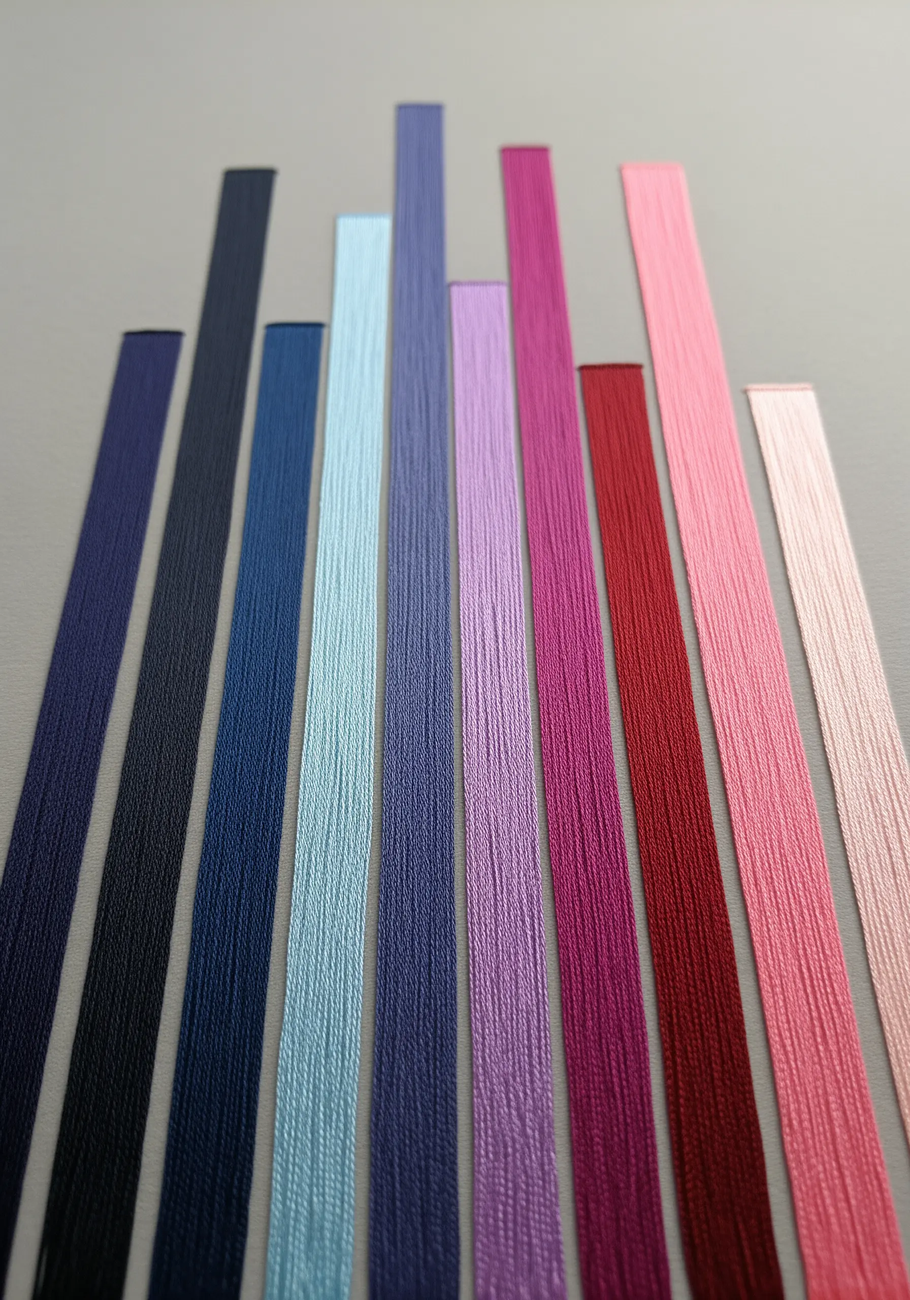 Flat, smooth bars of colorful embroidery floss laid side-by-side on a gray background.