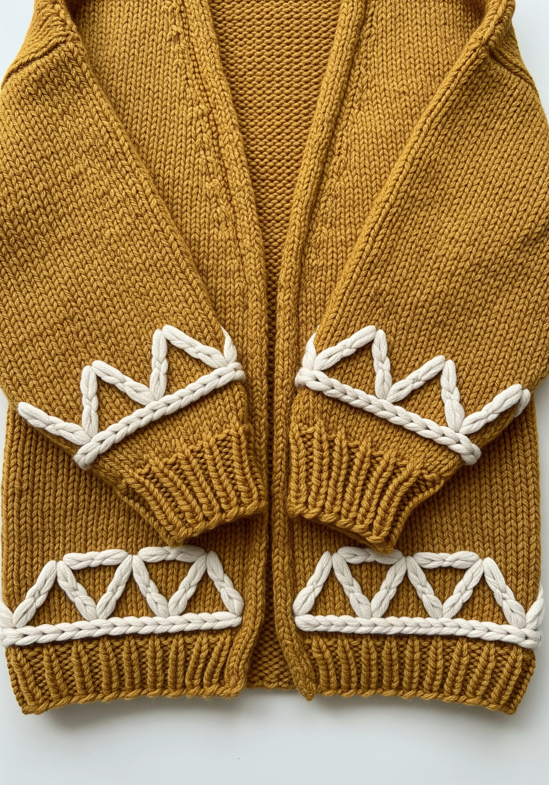 Geometric pattern in thick white yarn couched onto a chunky mustard yellow cardigan.