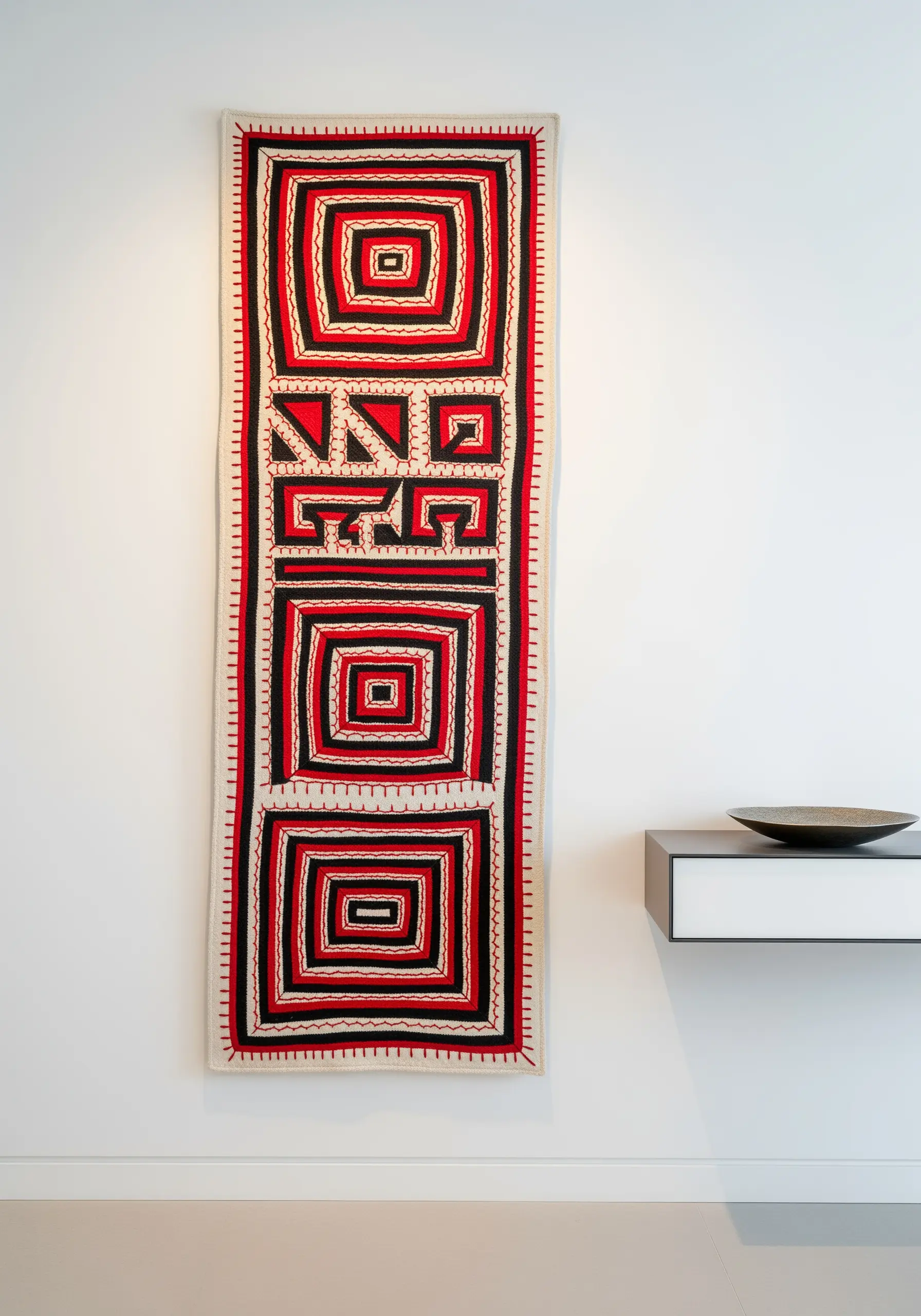A modern wall with a narrow, geometric Naga-style embroidered runner in red, black, and white.
