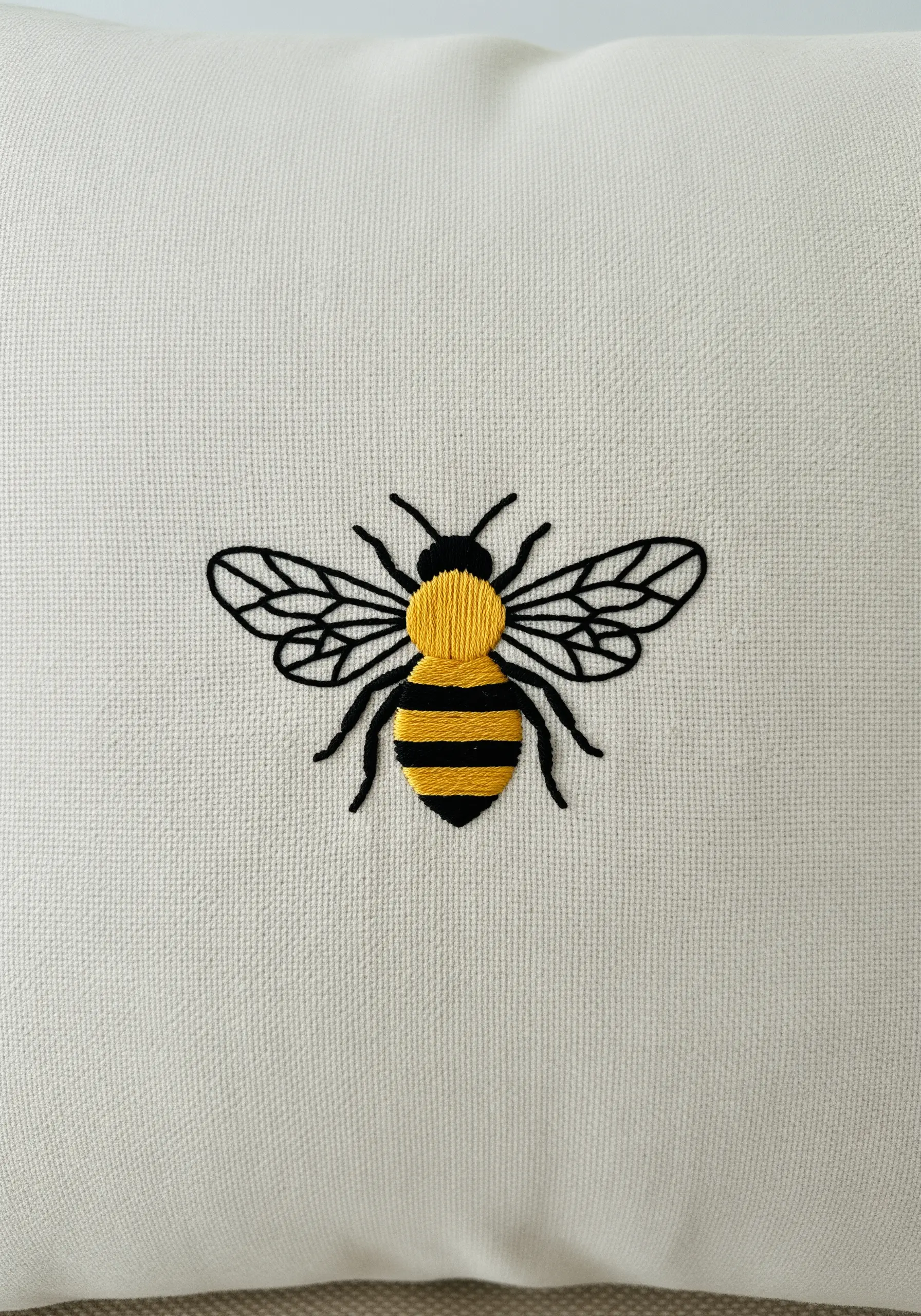 A bold, graphic embroidered bee with clean black outlines and yellow satin-stitched stripes.