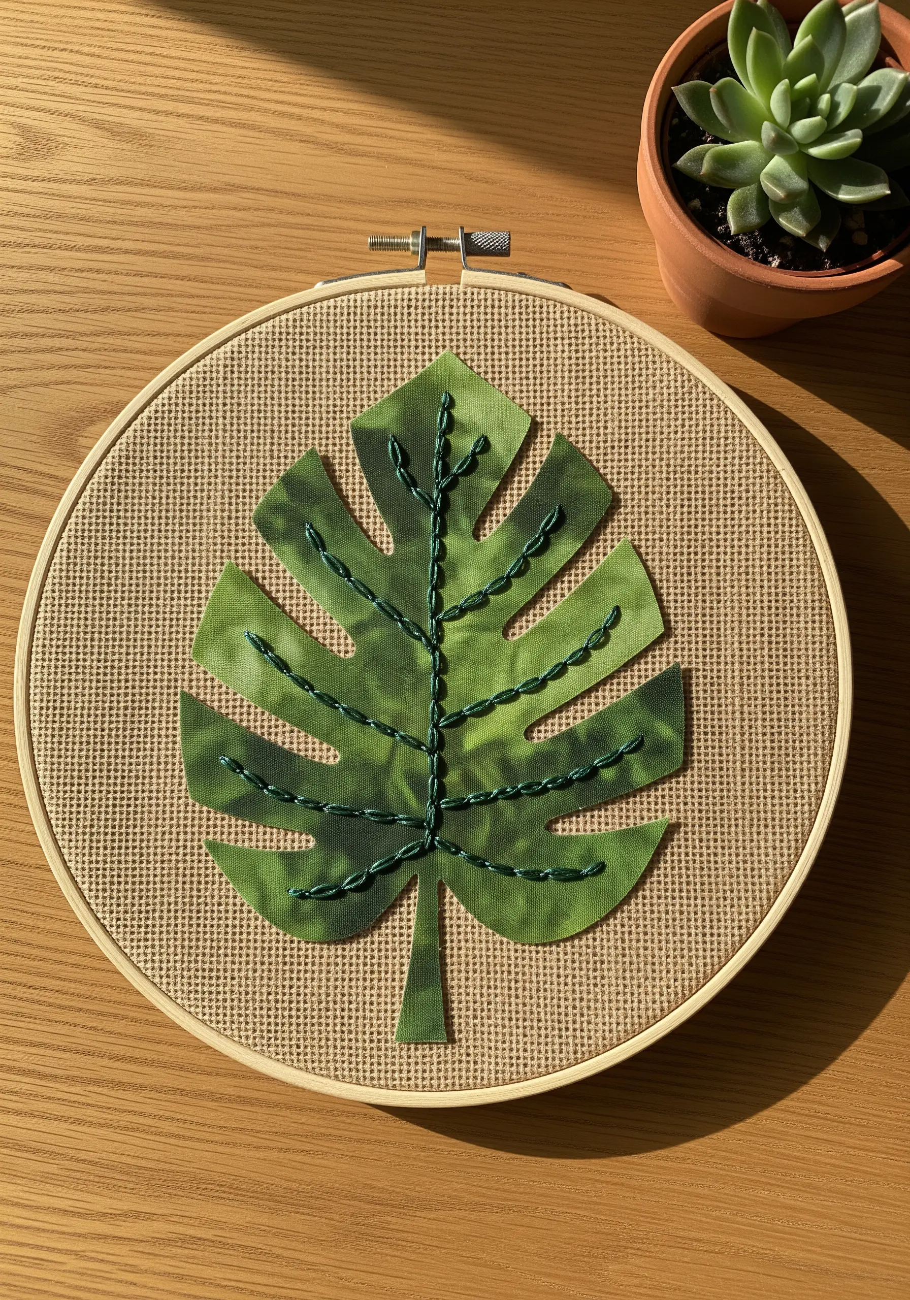Green patterned fabric monstera leaf with chain stitch embroidery details.