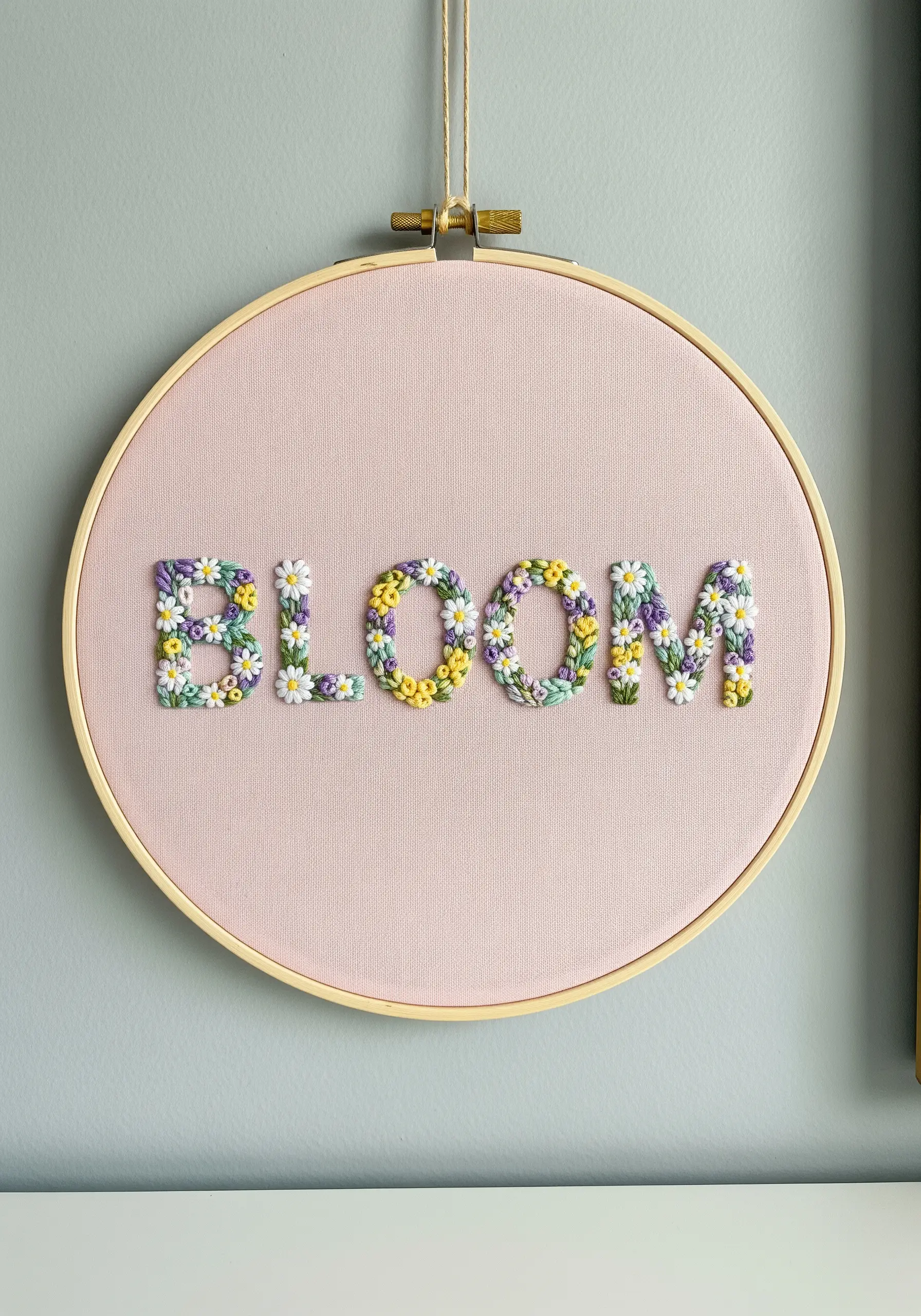 The word 'BLOOM' with each letter filled with tiny embroidered flowers and leaves.